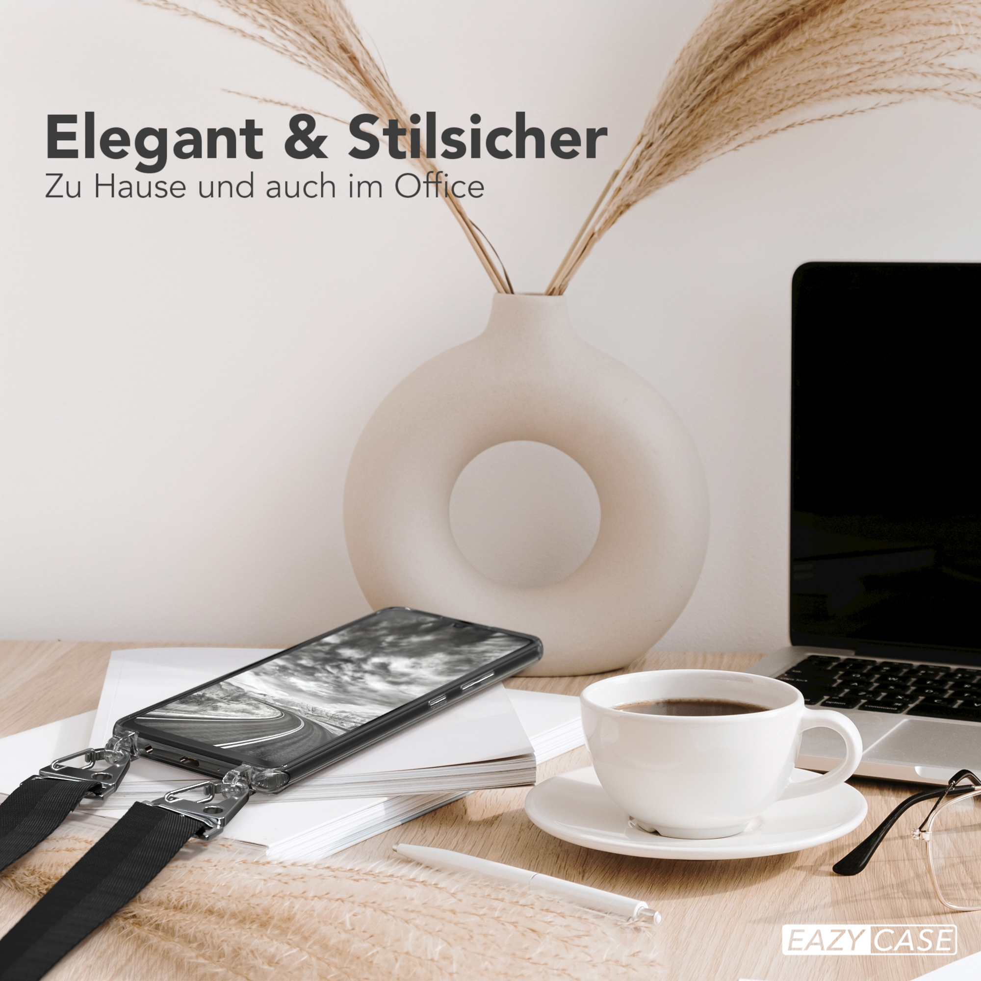 Ein Telefon mit schwarzer Hülle auf einem Schreibtisch mit Kaffeetasse und Laptop.