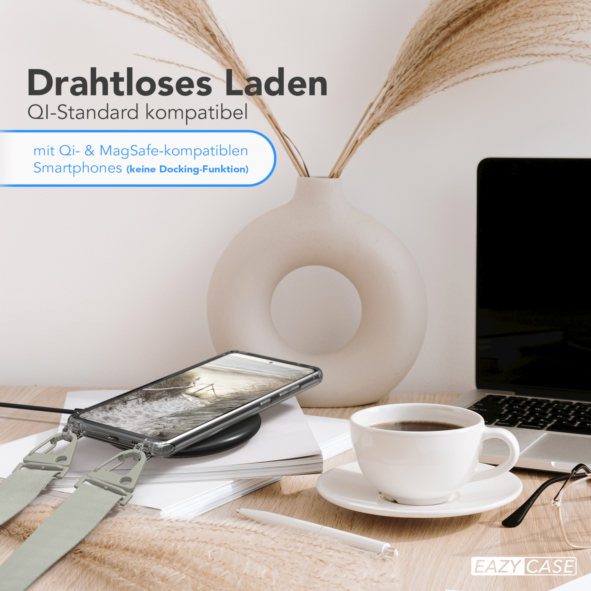 Ein Telefon mit Hülle, Riemen und kabellosem Ladegerät, Kaffee und Deko auf dem Schreibtisch.
