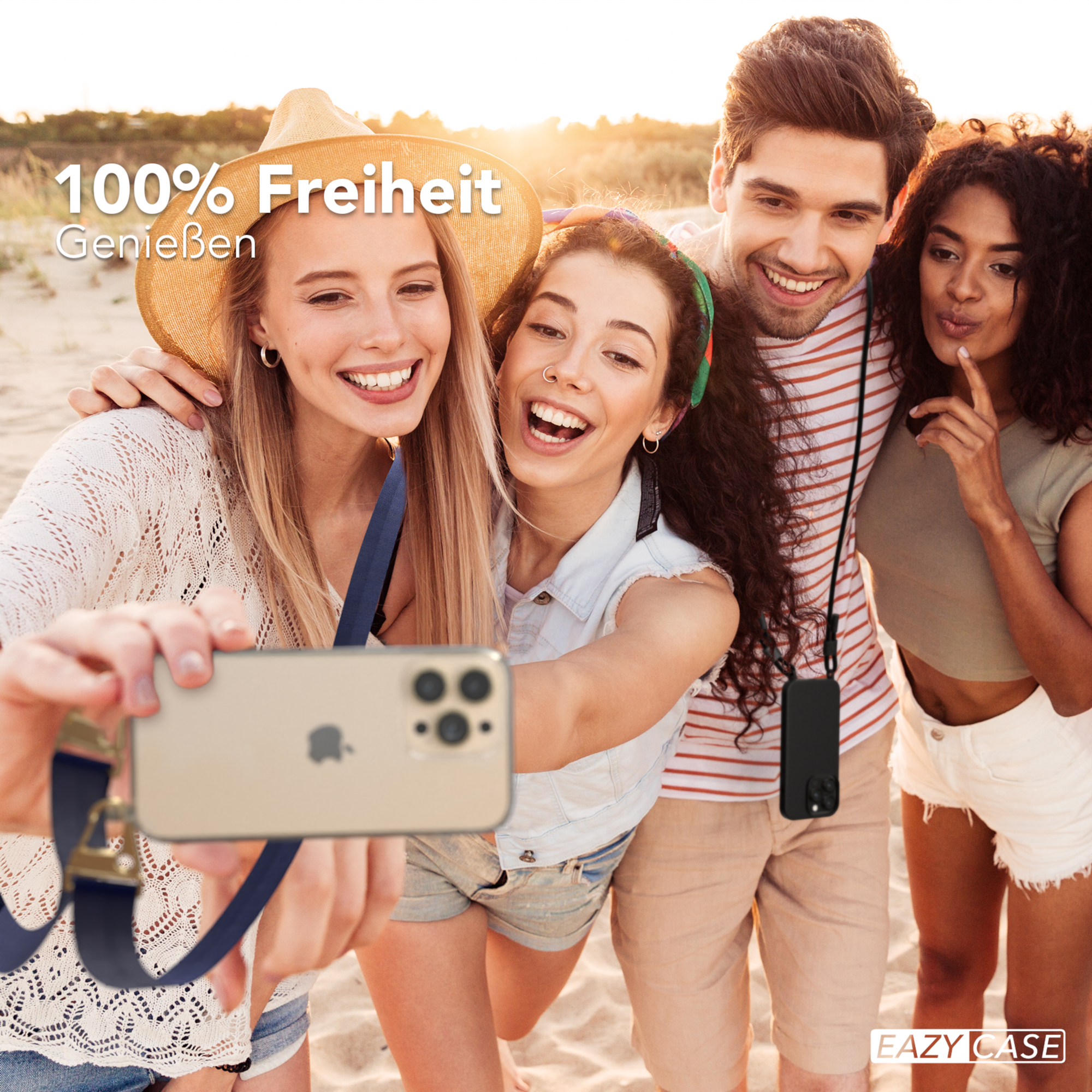 Vier Personen machen ein Selfie am Strand. Sie lächeln und halten ein Telefon mit Riemen.