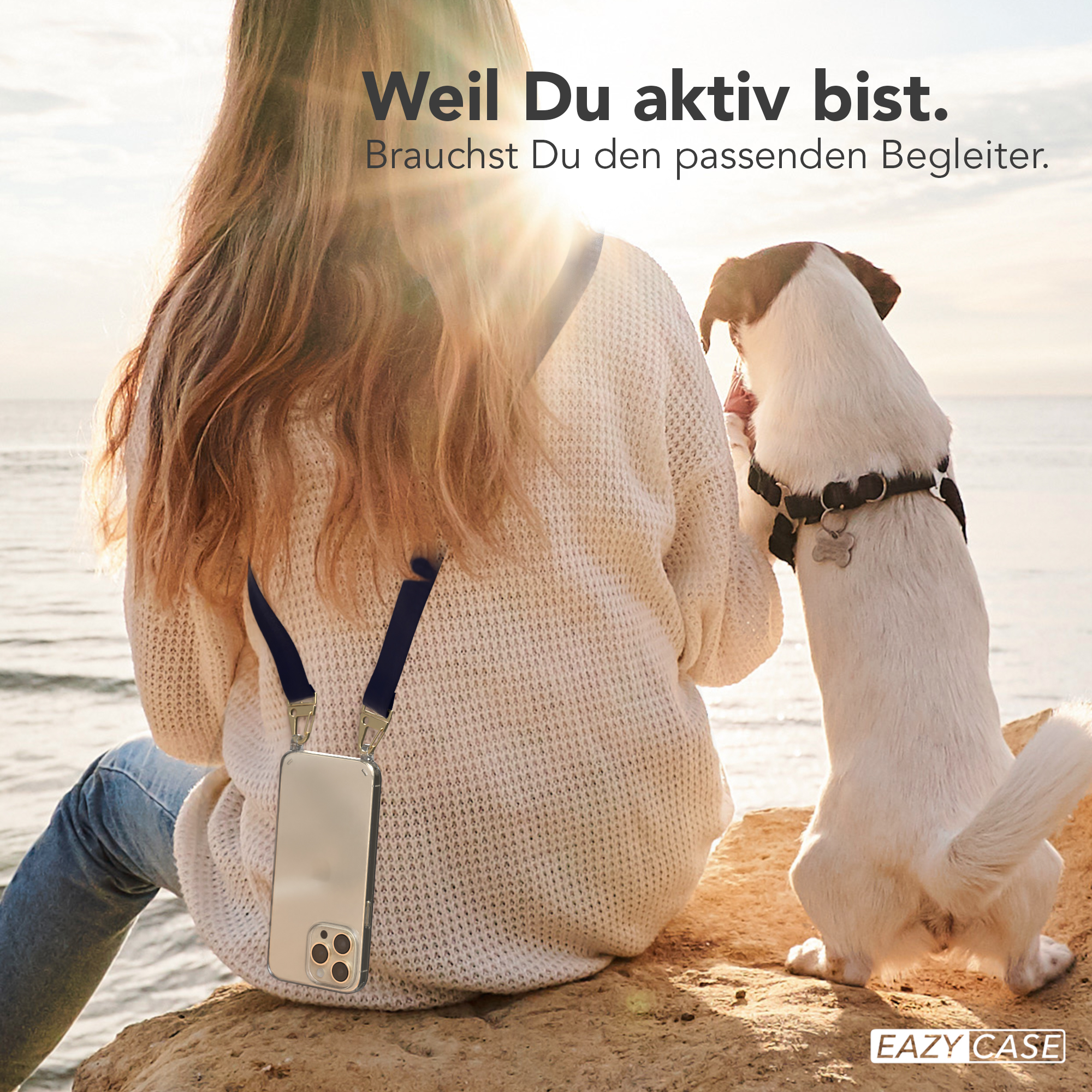 Eine Frau mit Handyhülle um den Hals sitzt auf einem Felsen. Ein Hund steht neben ihr.