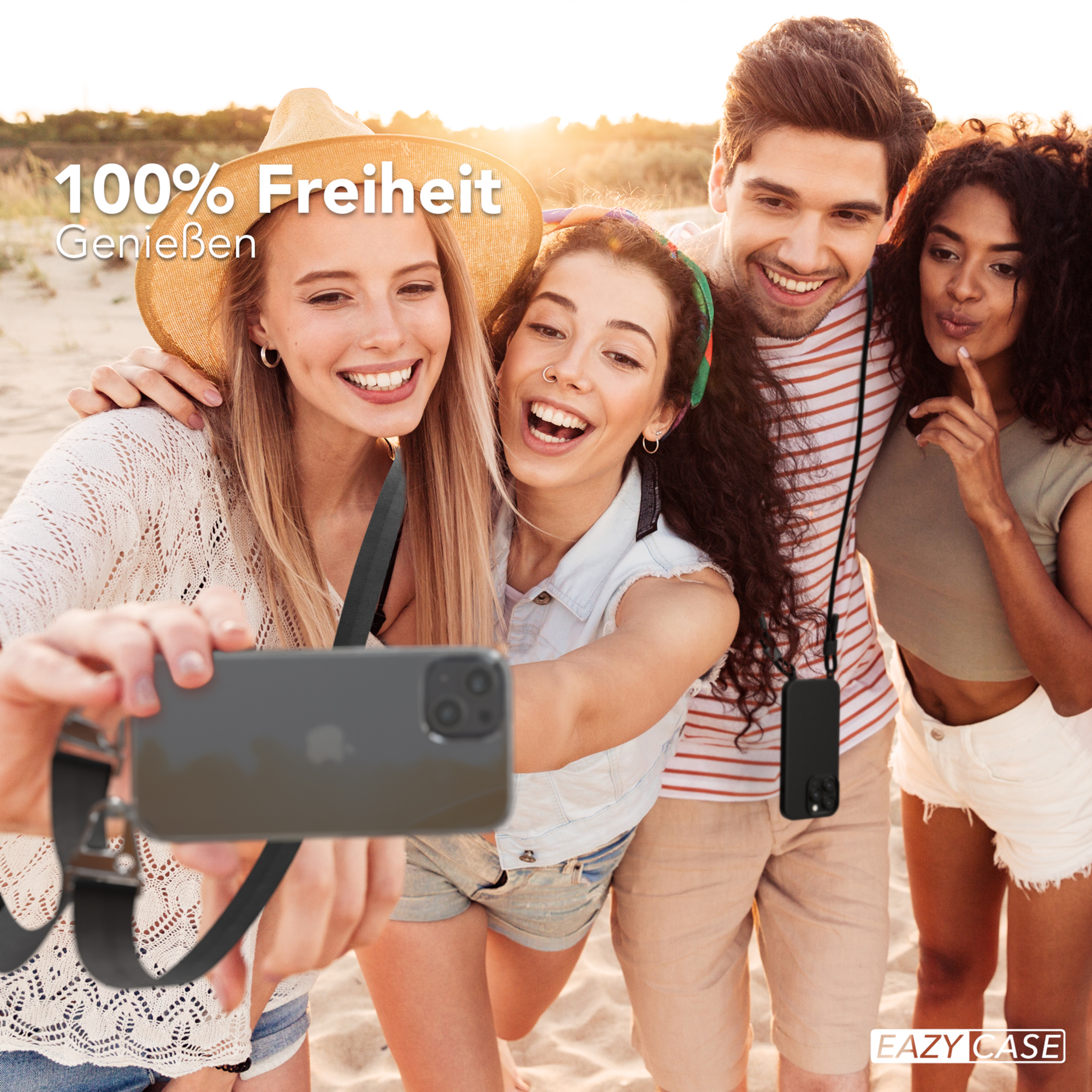 Vier Leute lächeln und machen ein Selfie. Sie sind am Strand. Einer hält das Handy.