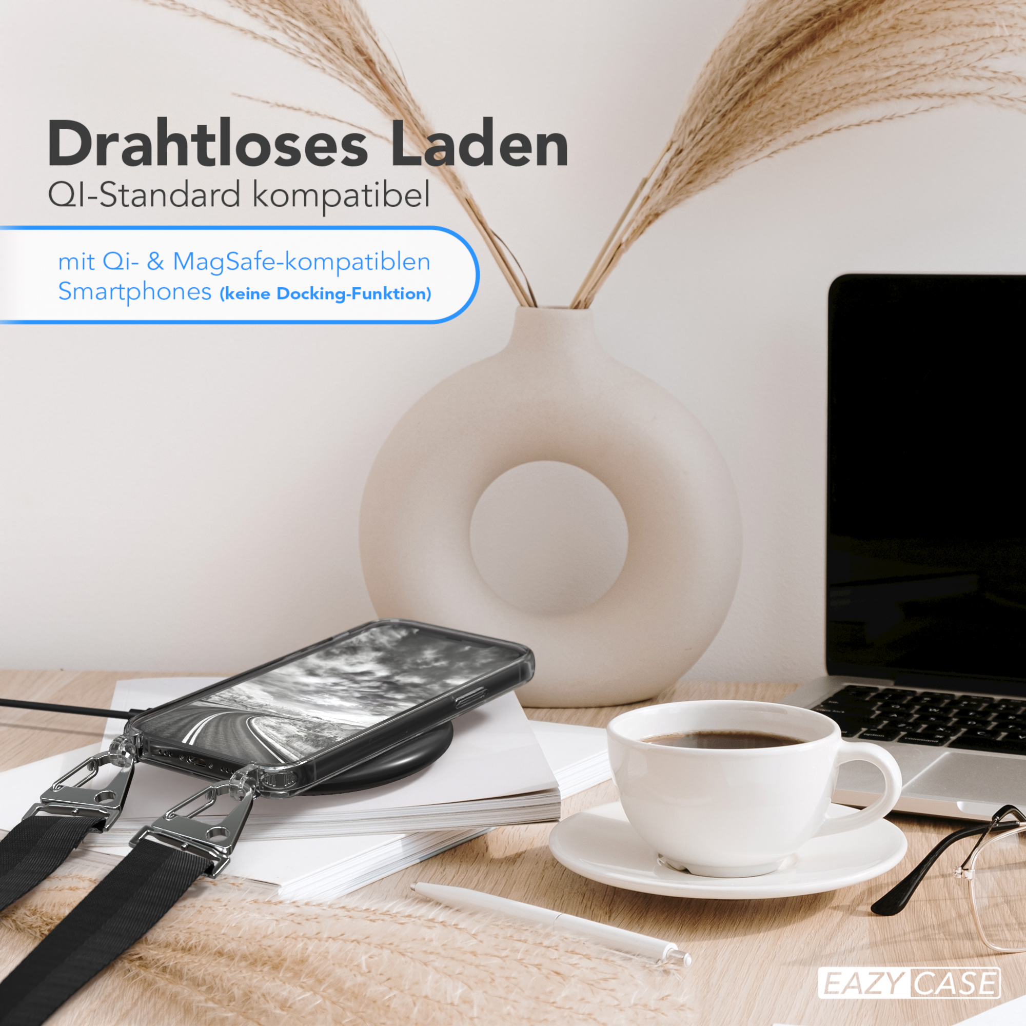 Telefon auf kabellosem Ladegerät, Kaffeetasse, Vase mit Pflanzen, Laptop und Brille auf dem Schreibtisch.