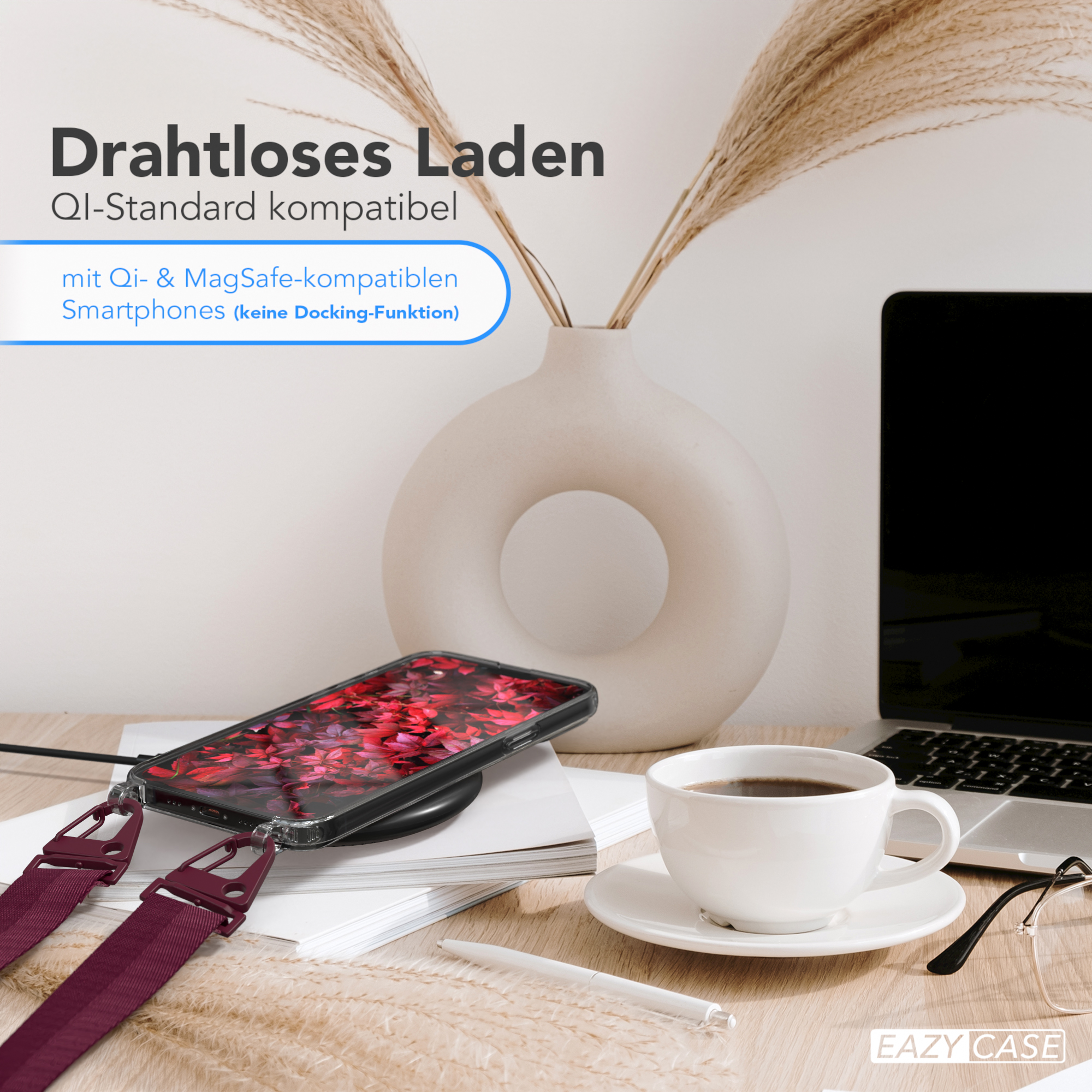 Ein Telefon auf einem kabellosen Ladegerät, eine Kaffeetasse und ein Laptop stehen auf einem Tisch.