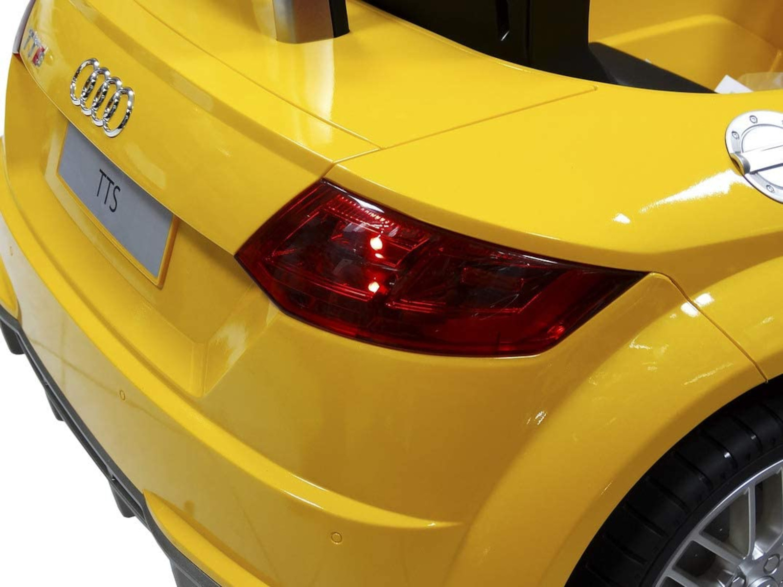 Gelbes Spielzeugauto hinten. Rücklicht, Chromabzeichen. Weißer Hintergrund.