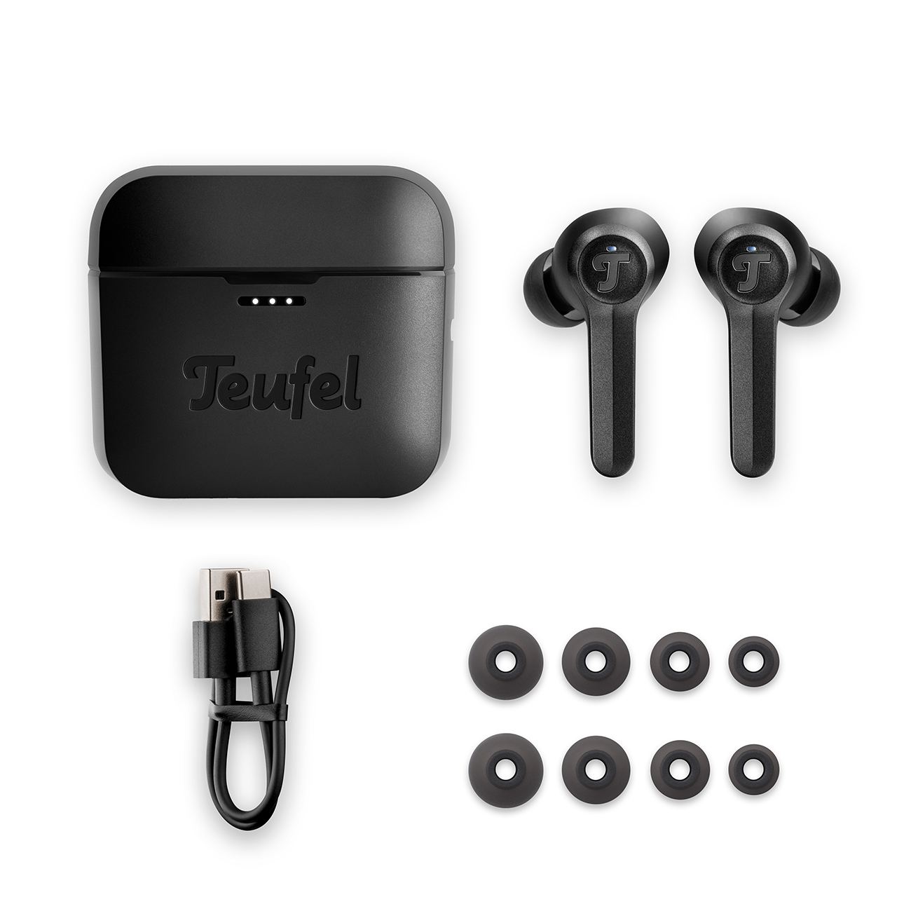 Schwarze Ohrhörer mit Ladecase, USB-Kabel und zusätzlichen Ohrstöpseln auf einer weißen Oberfläche angeordnet.