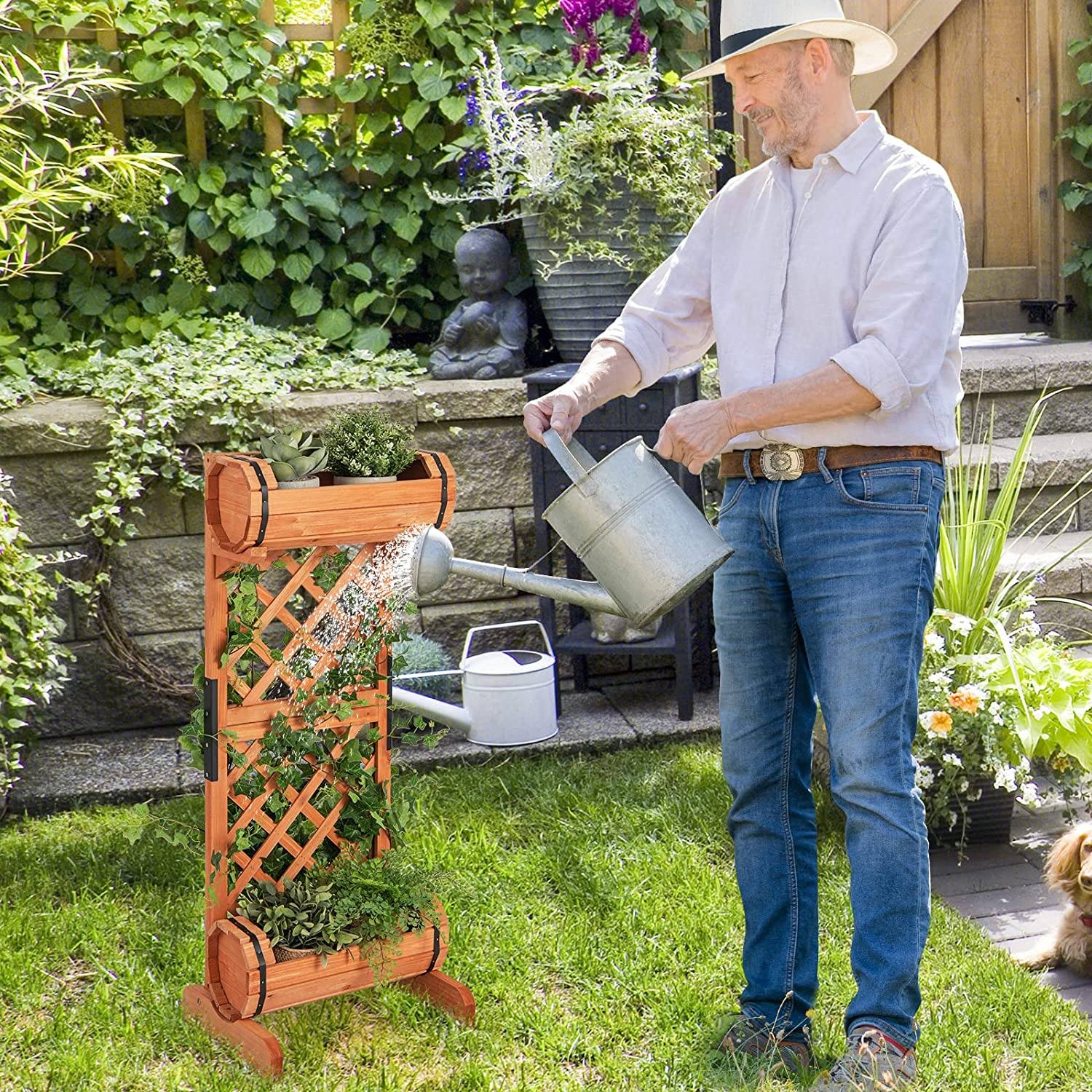 Ein Mann gießt Pflanzen in einem Holzpflanzer. Der Hintergrund zeigt einen grünen Garten.