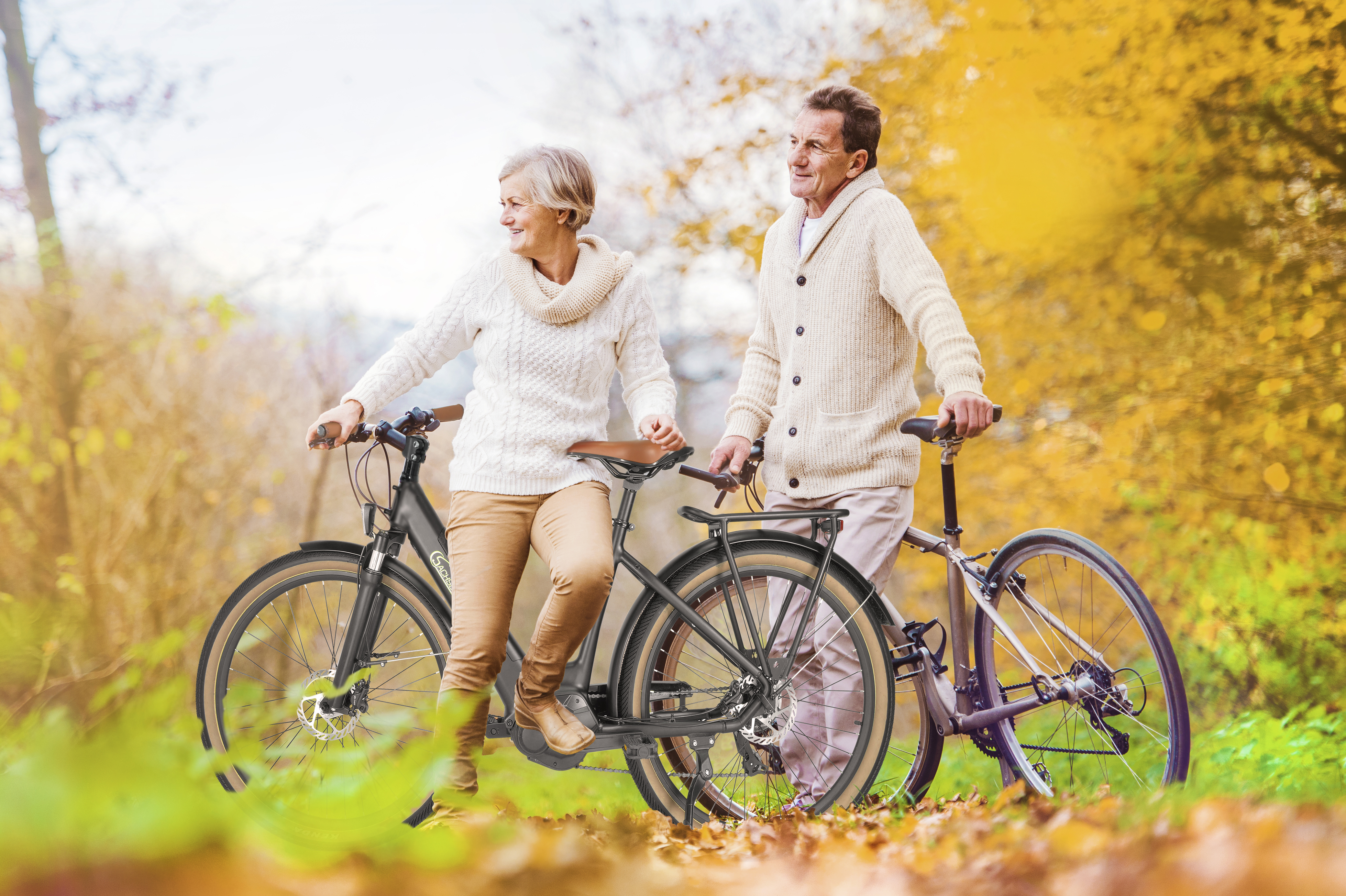 Een ouder echtpaar fietst in een park in de herfst. Ze lachen.