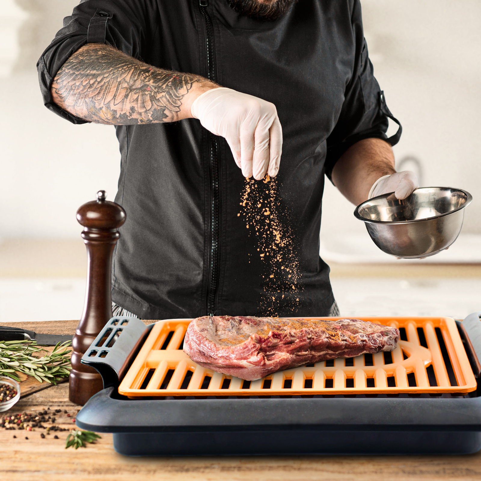 Un chef espolvorea condimento sobre un bistec en una parrilla, con un molinillo de pimienta visible.