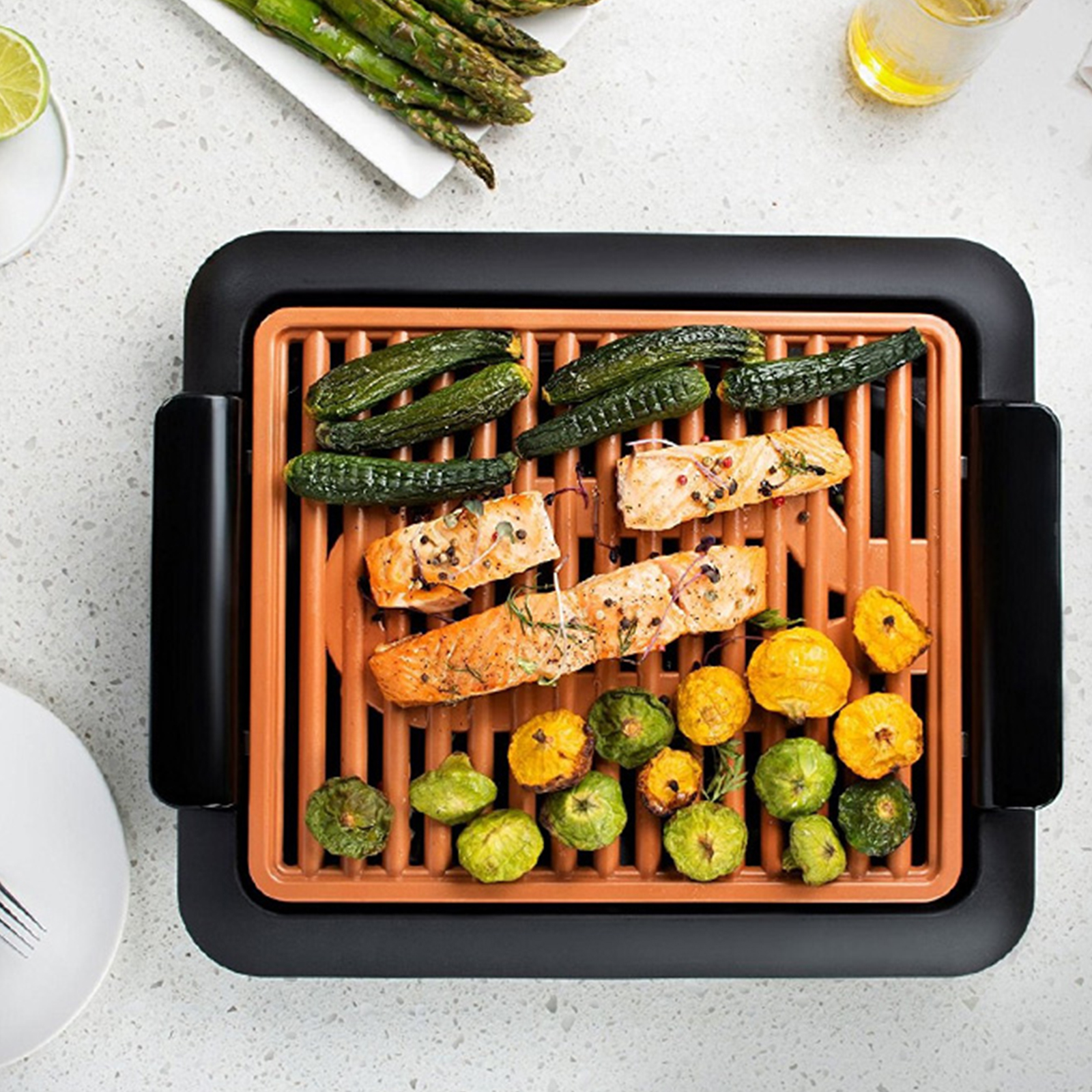Salmón y verduras a la parrilla en una parrilla negra con fondo blanco.
