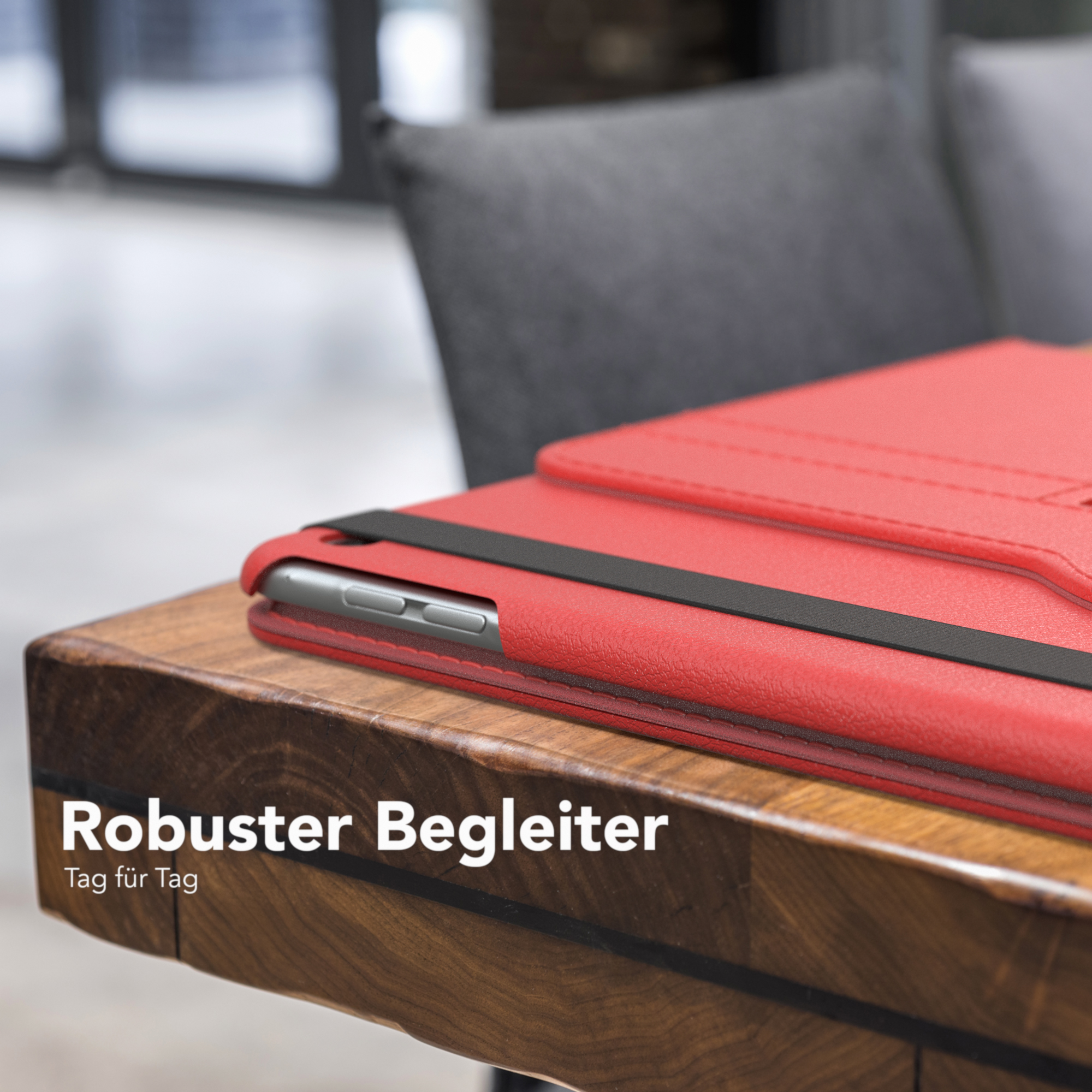 Rotes Tablet-Case auf einem Holztisch. Ein schwarzes Band ist sichtbar. Text: Robuster Begleiter.