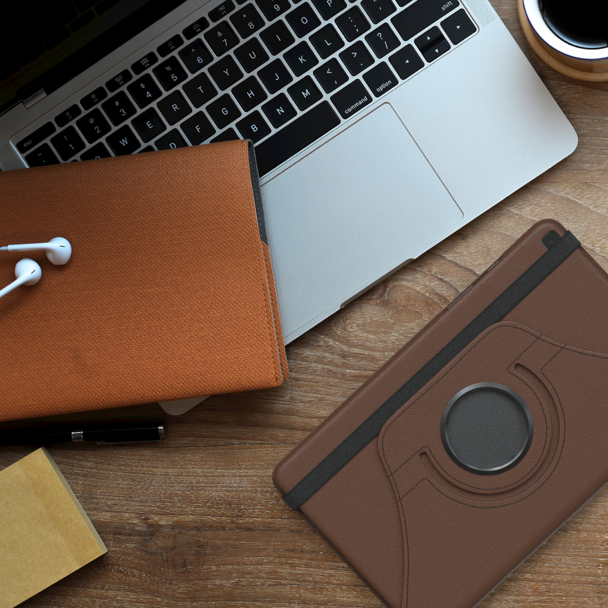 Holzschreibtisch mit Tablet, Laptop und anderen Gegenständen. Das Tablet befindet sich in einem braunen Gehäuse.