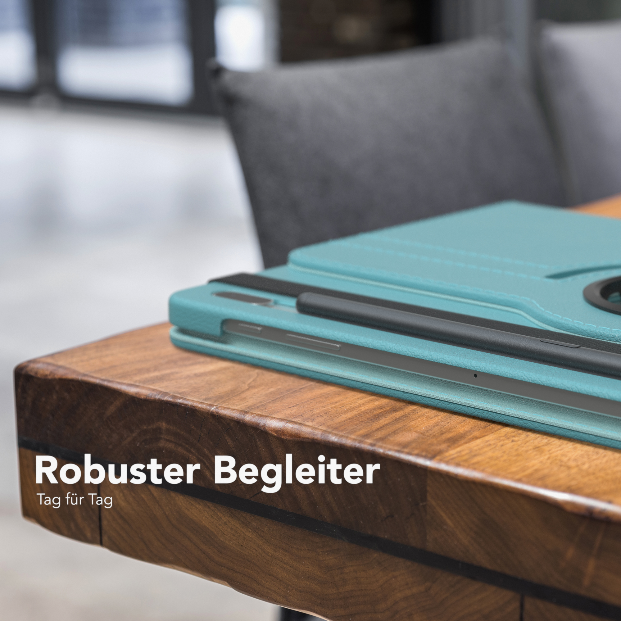 Tablet in teal Hülle auf Holztisch. Dunkelgrauer Stuhl im Hintergrund.