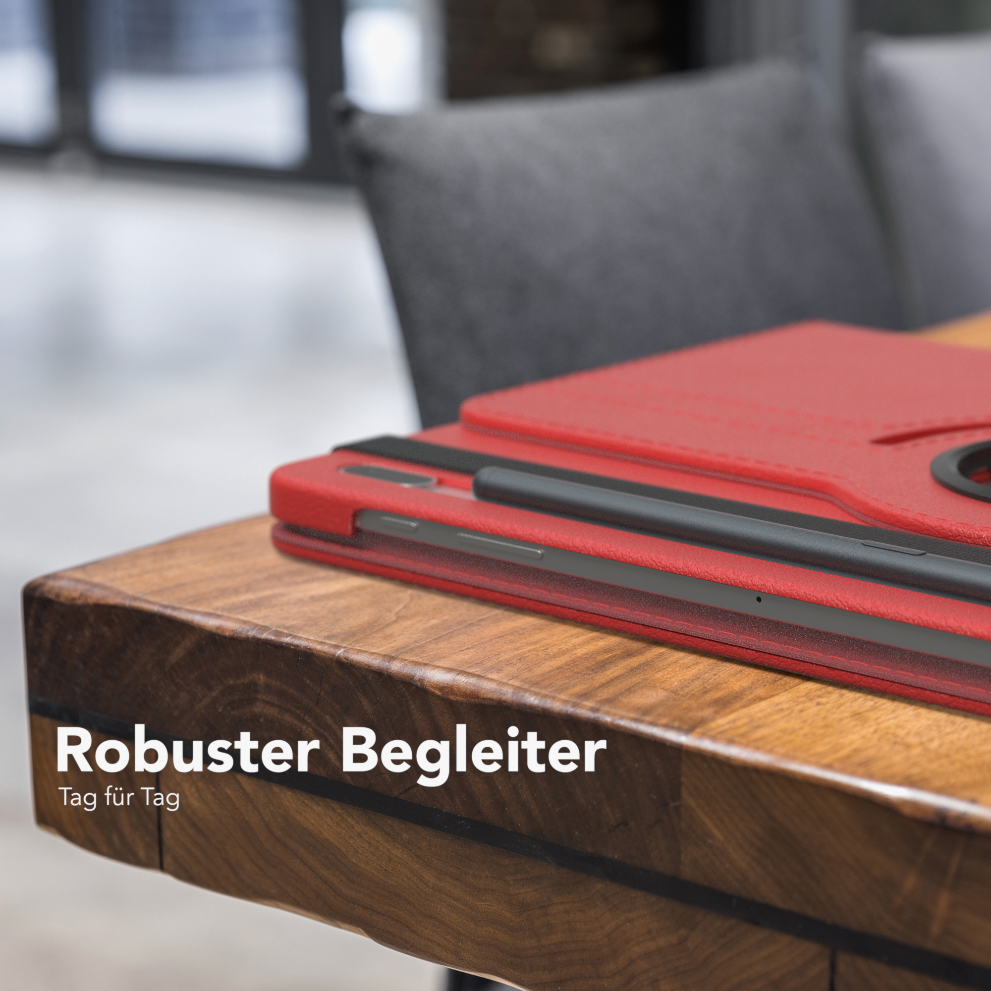 Rote Tablethülle auf einem Holztisch. Schwarzer Stift und Text auf der Hülle: 'Robuster Begleiter'.