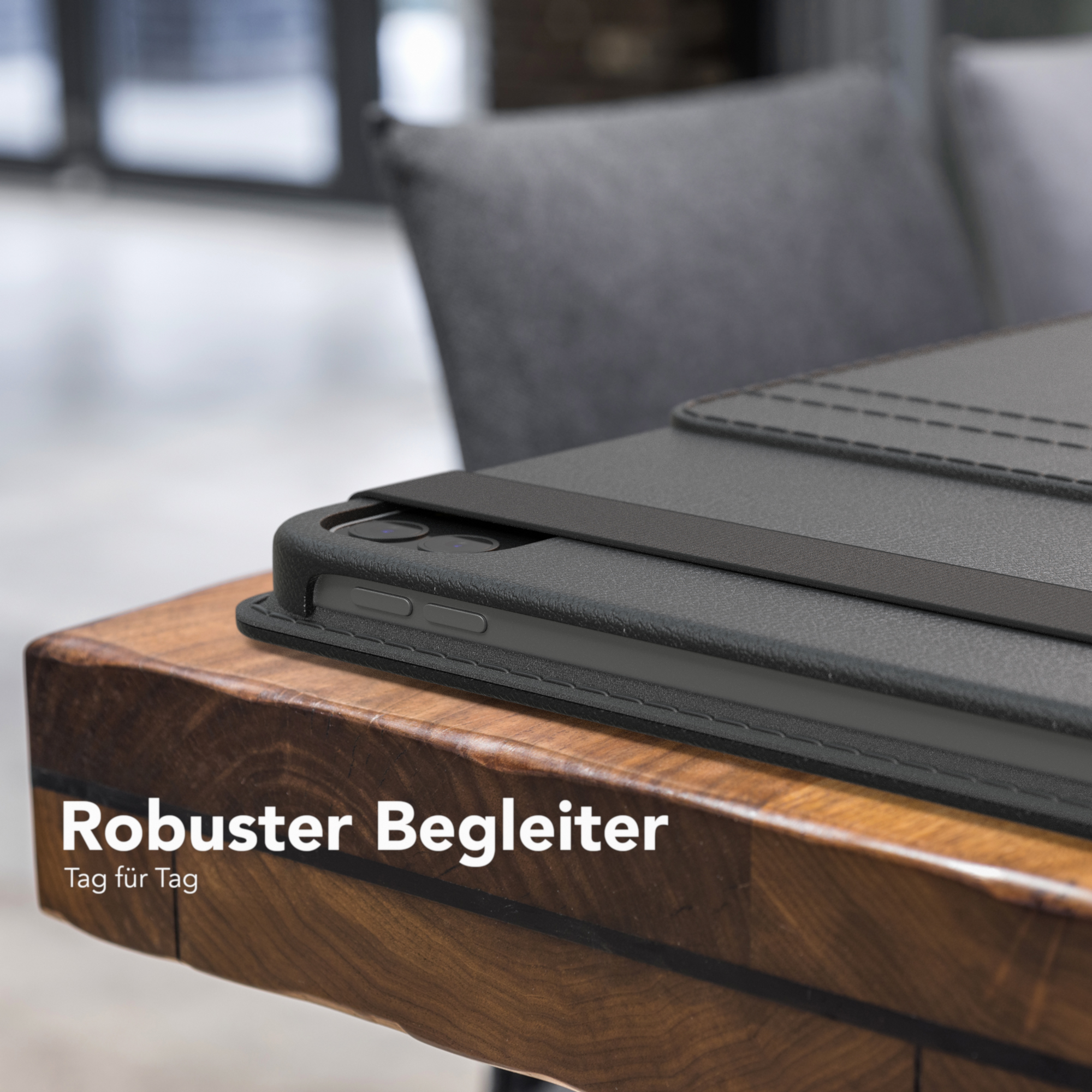 Tablet auf Holztisch, in schwarzem Gehäuse. Text „Robuster Begleiter“ steht auf dem Tisch.