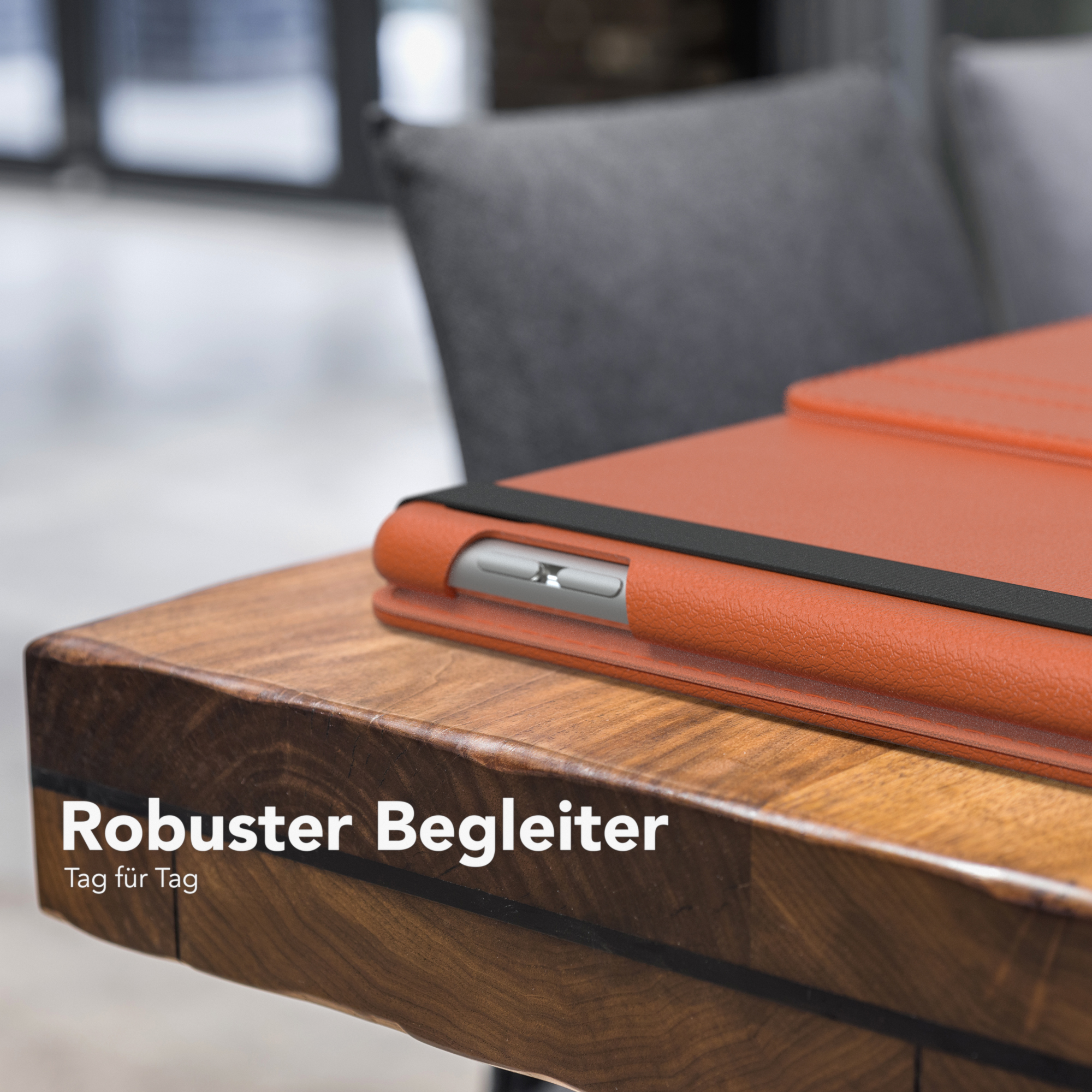Eine orangefarbene Tablethülle auf einem Holztisch mit einem schwarzen Gummiband.