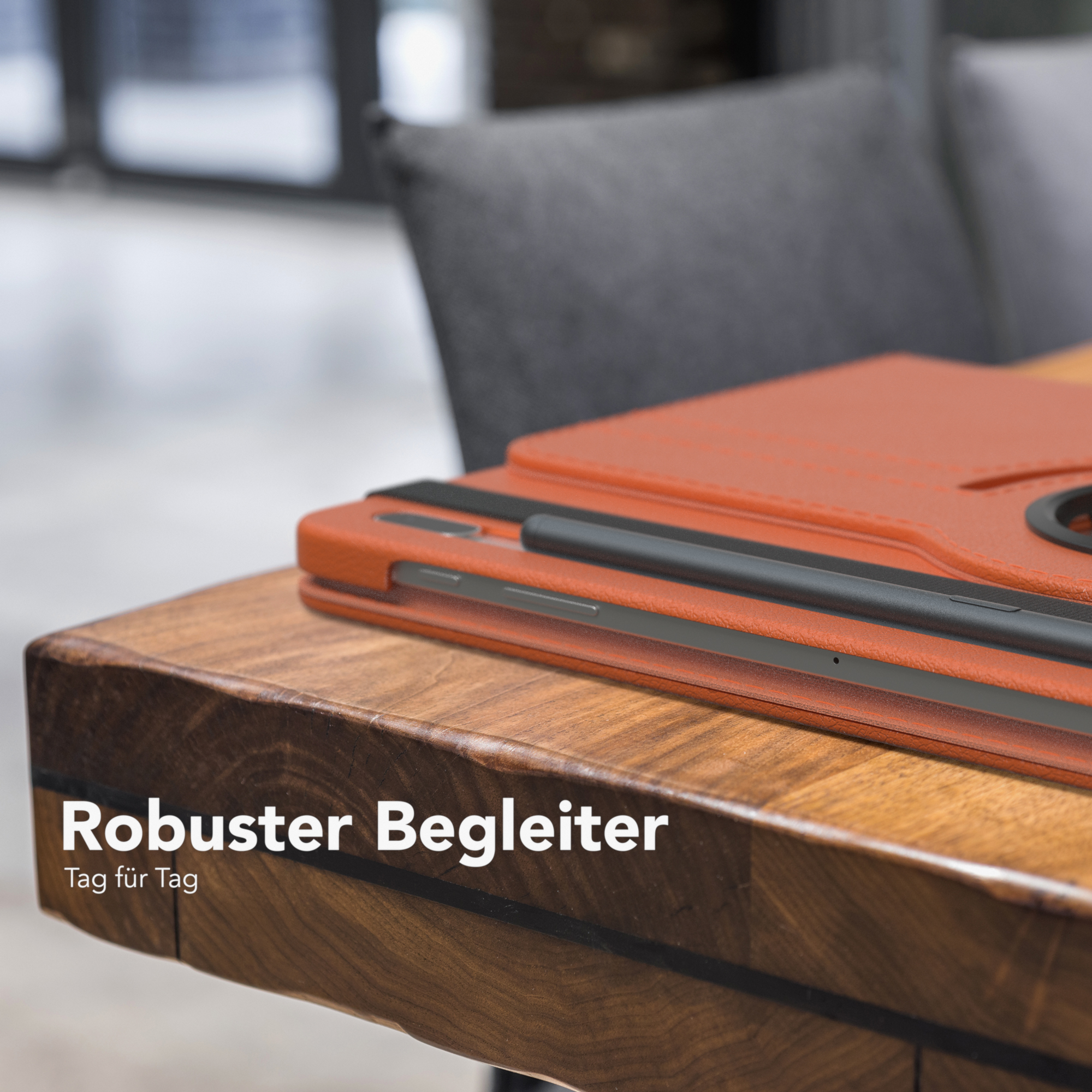 Nahaufnahme einer orangefarbenen Tablet-Hülle auf einem Holztisch. Schwarzer Stift sichtbar.