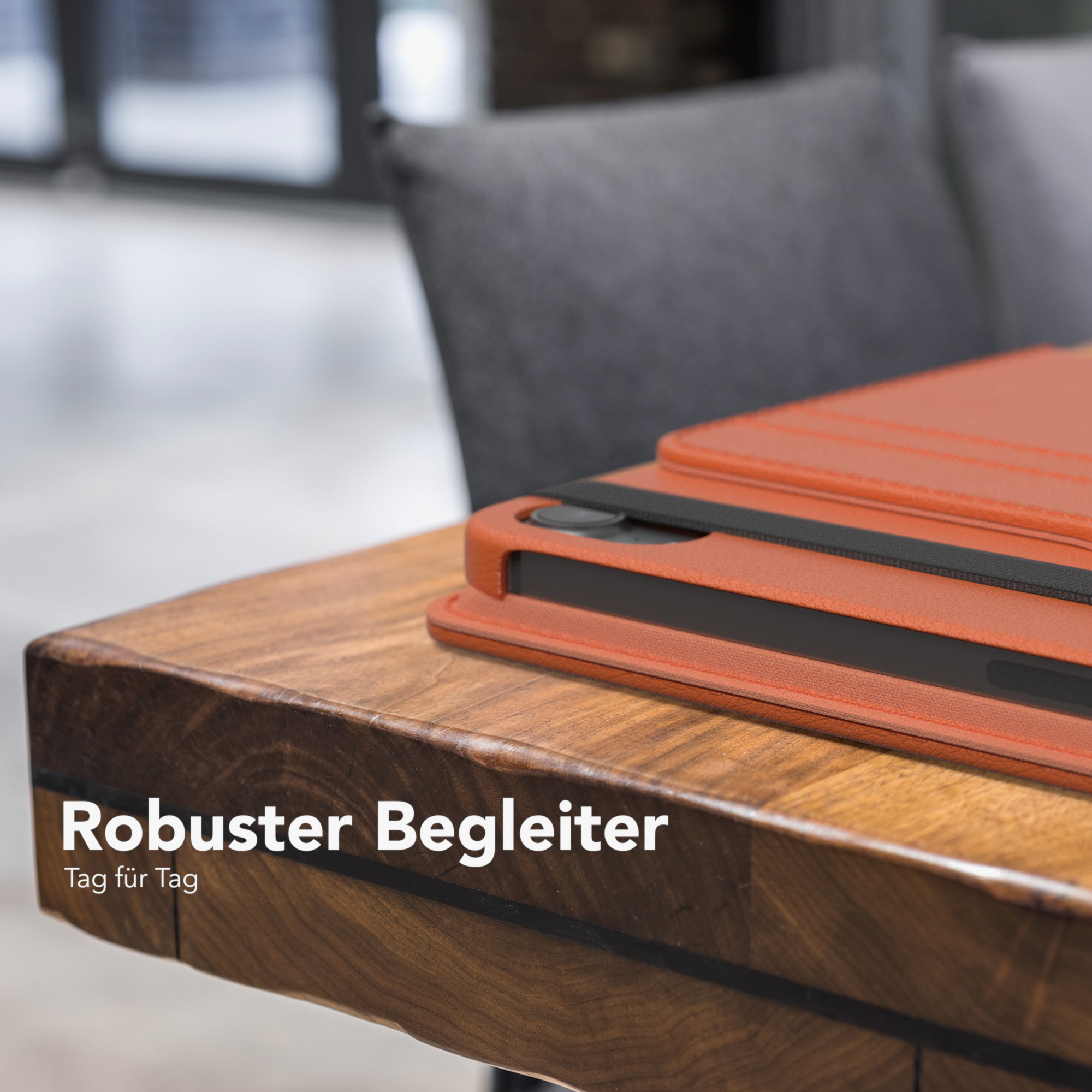 Orangefarbene Handyhülle auf Holztisch. Schwarzer Streifen. Text: Robuster Begleiter.