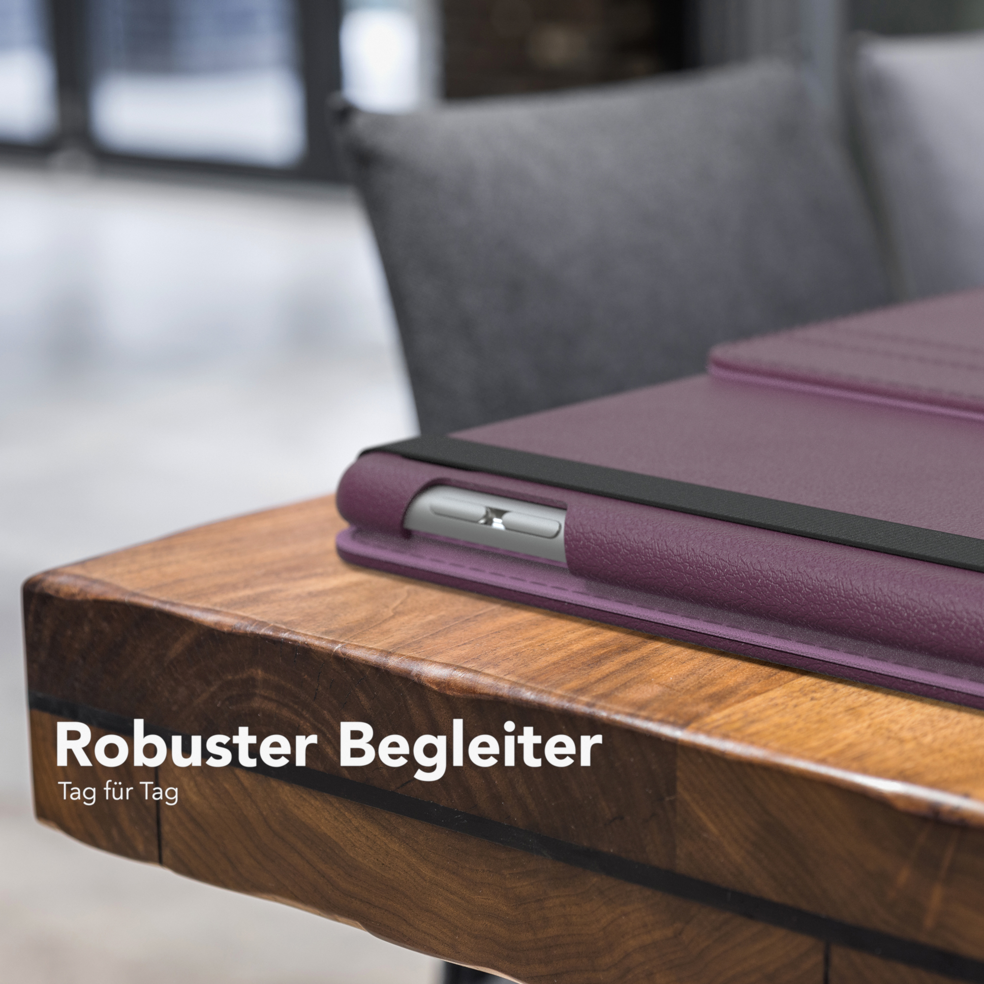 Tablet in lila Hülle auf Holztisch, Text: Robuster Begleiter Tag für Tag. Grauer Stuhl sichtbar.