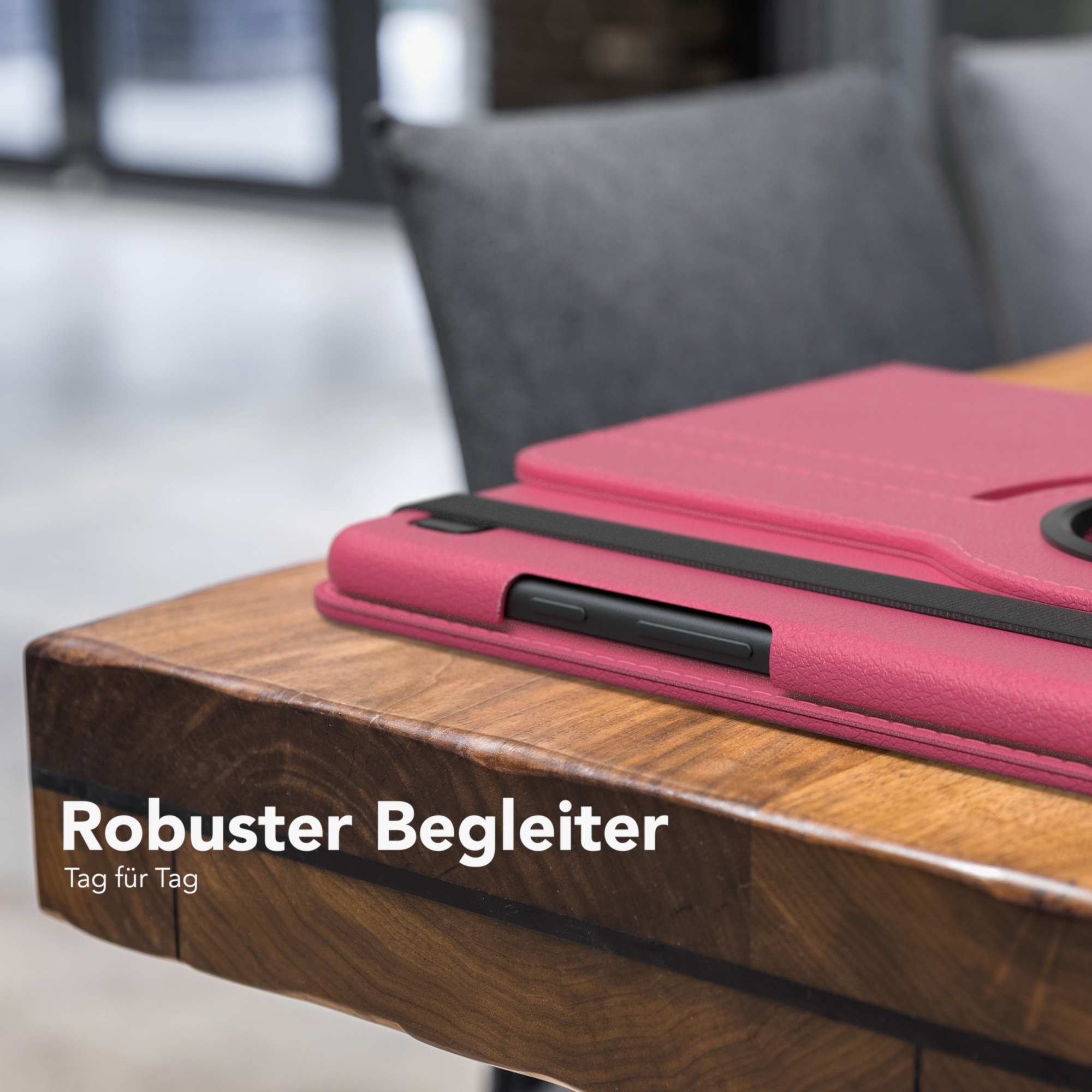 Tablet-Hülle auf Holztisch. Dunkelrosa Hülle. Schwarzer Riemen. Text: Robuster Begleiter.