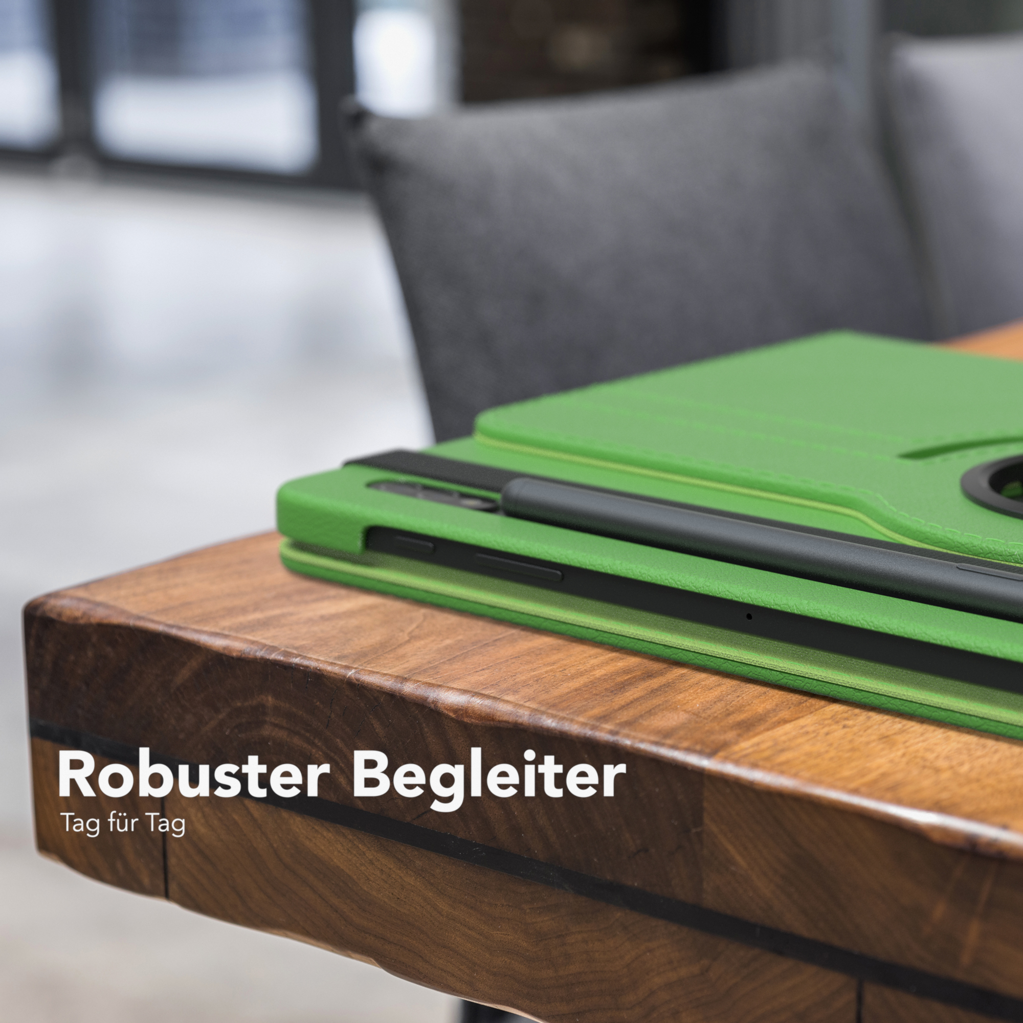 Grüne Tablethülle mit Tablet und Stift. Die Hülle liegt auf einem Holztisch.