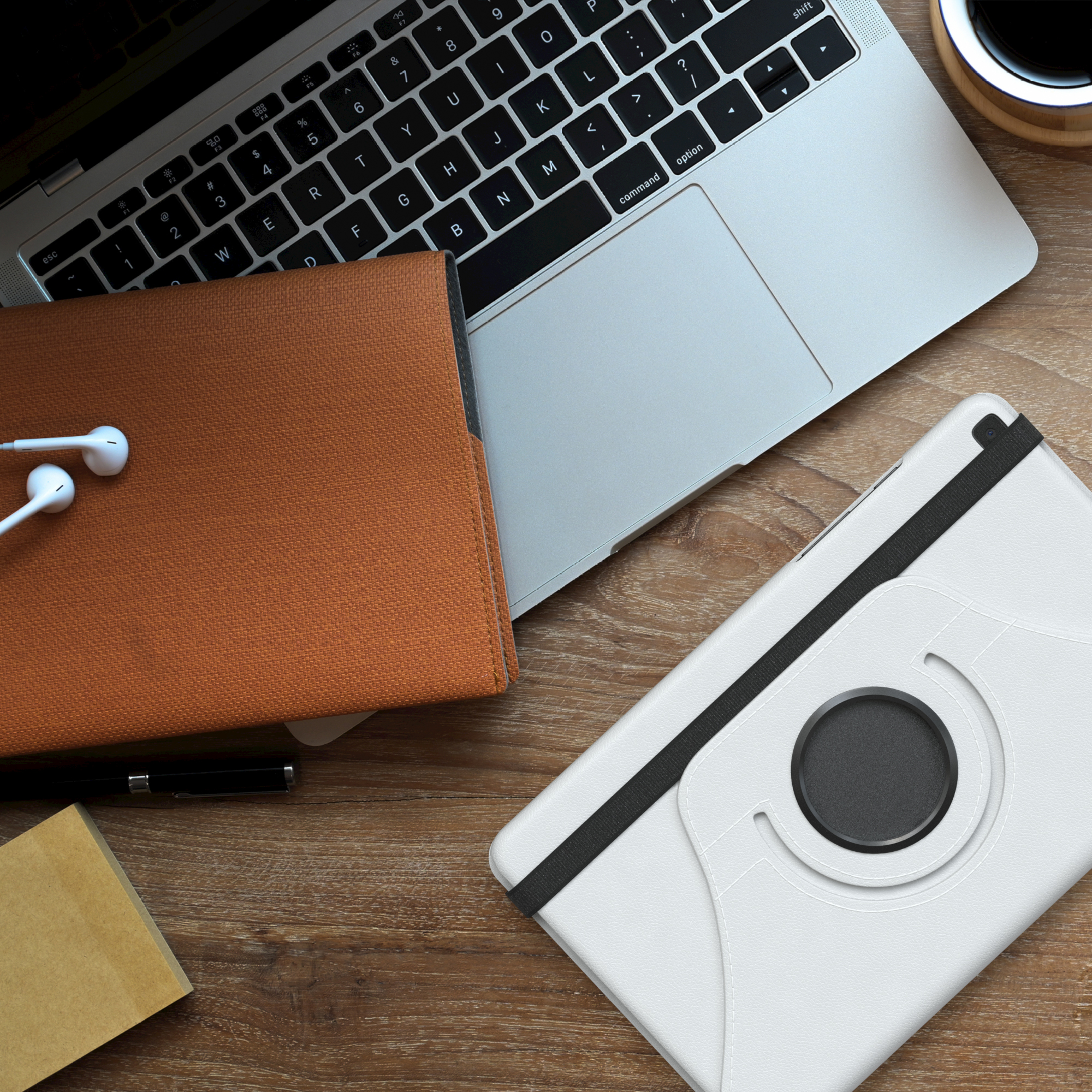 Tablet, Laptop und Zubehör auf einem Holztisch. Weißes Tablet mit schwarzem Kreis.
