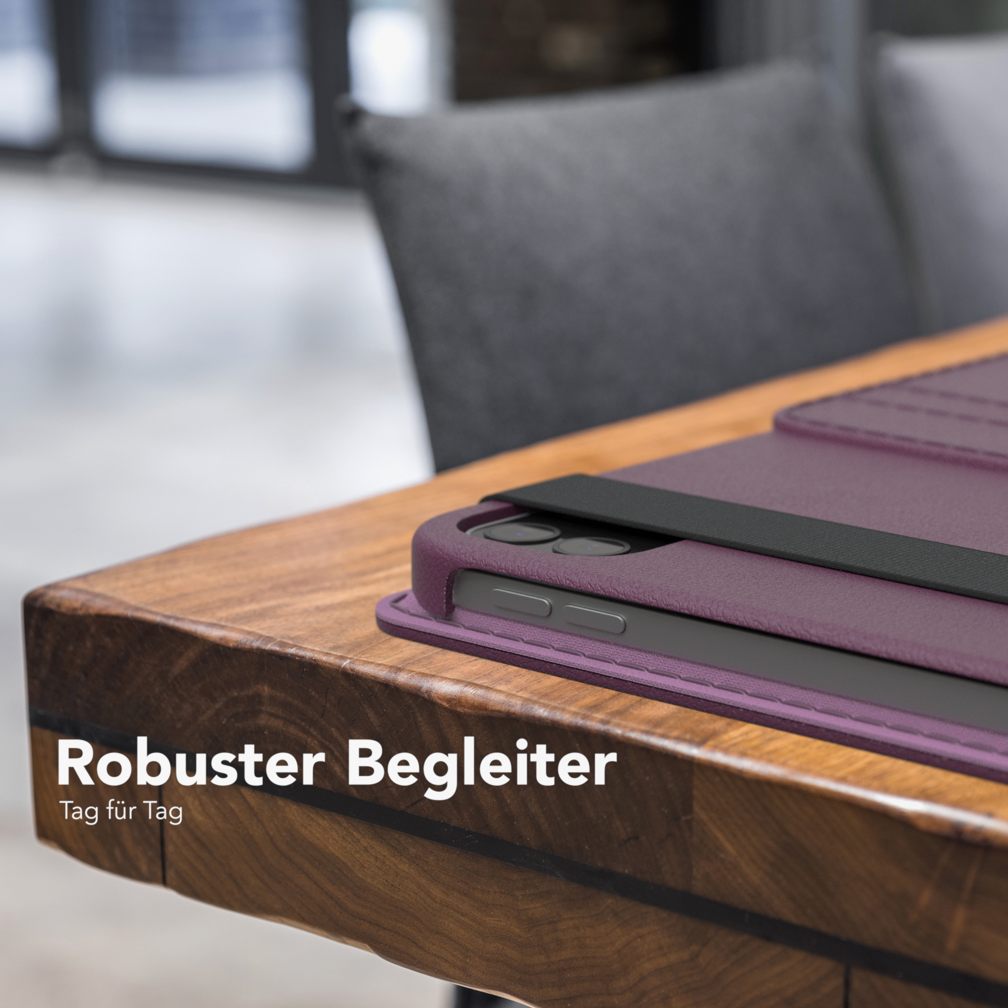 Tablet-Hülle auf Holztisch. Lila Hülle. Schwarzer Riemen. Text: Robuster Begleiter.