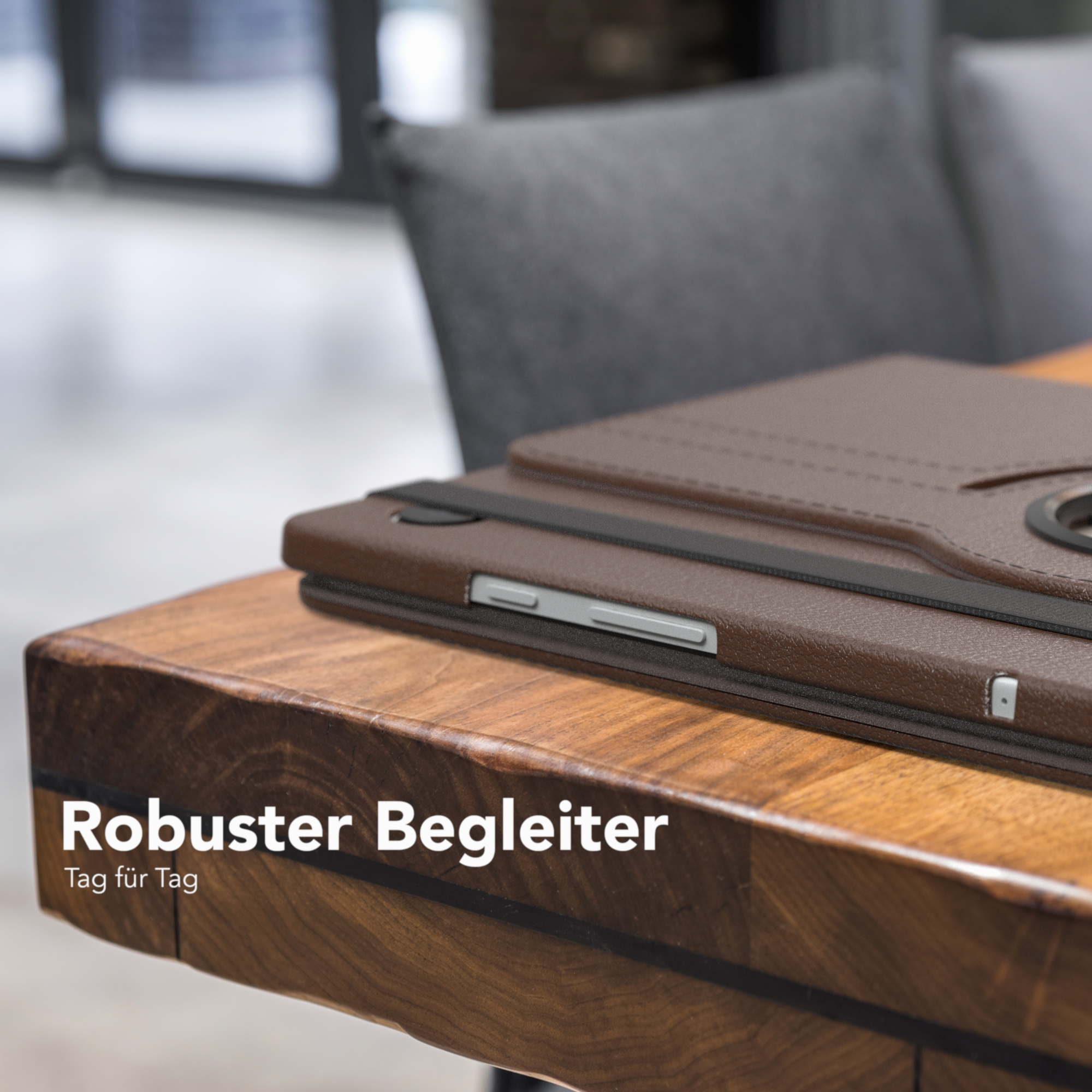 Eine braune Leder-Tablethülle auf einem Holztisch. Der Text lautet 'Robuster Begleiter, Tag für Tag'.