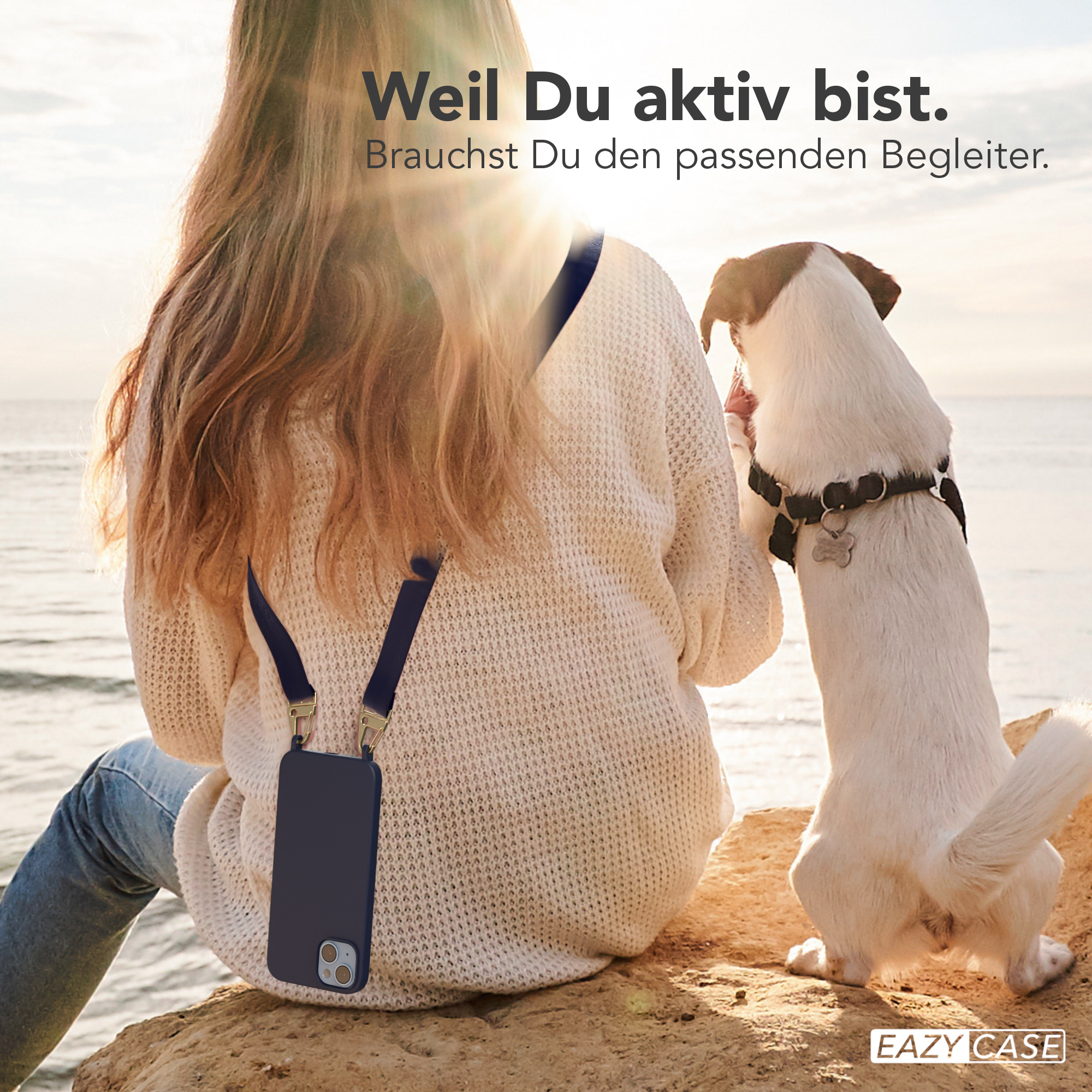 Eine Frau sitzt mit einer Handyhülle und einem Gurt auf einem Felsen. Ein Hund schaut sie an.