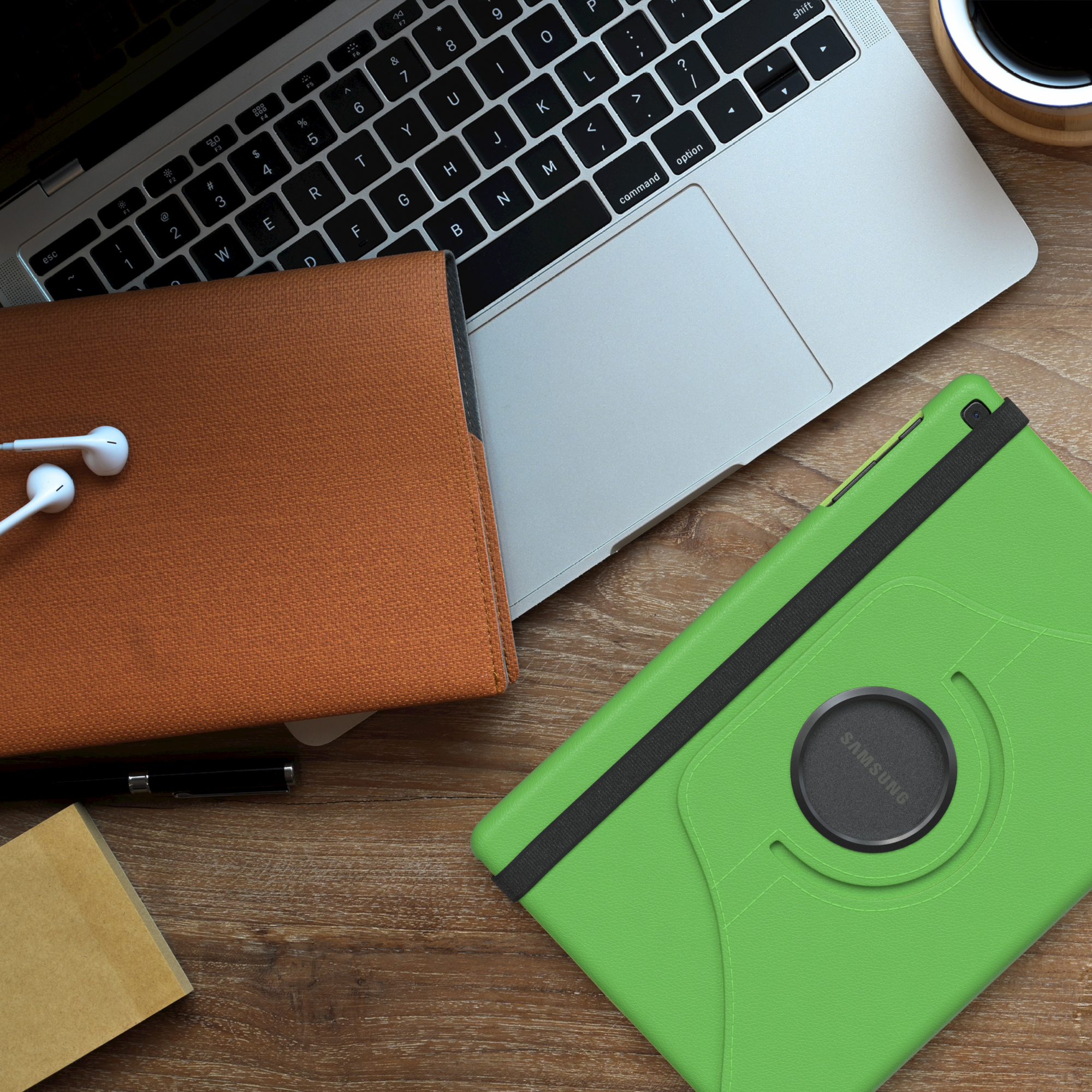 Laptop, Tablet, Kaffeetasse und Kopfhörer auf einem Holzschreibtisch.