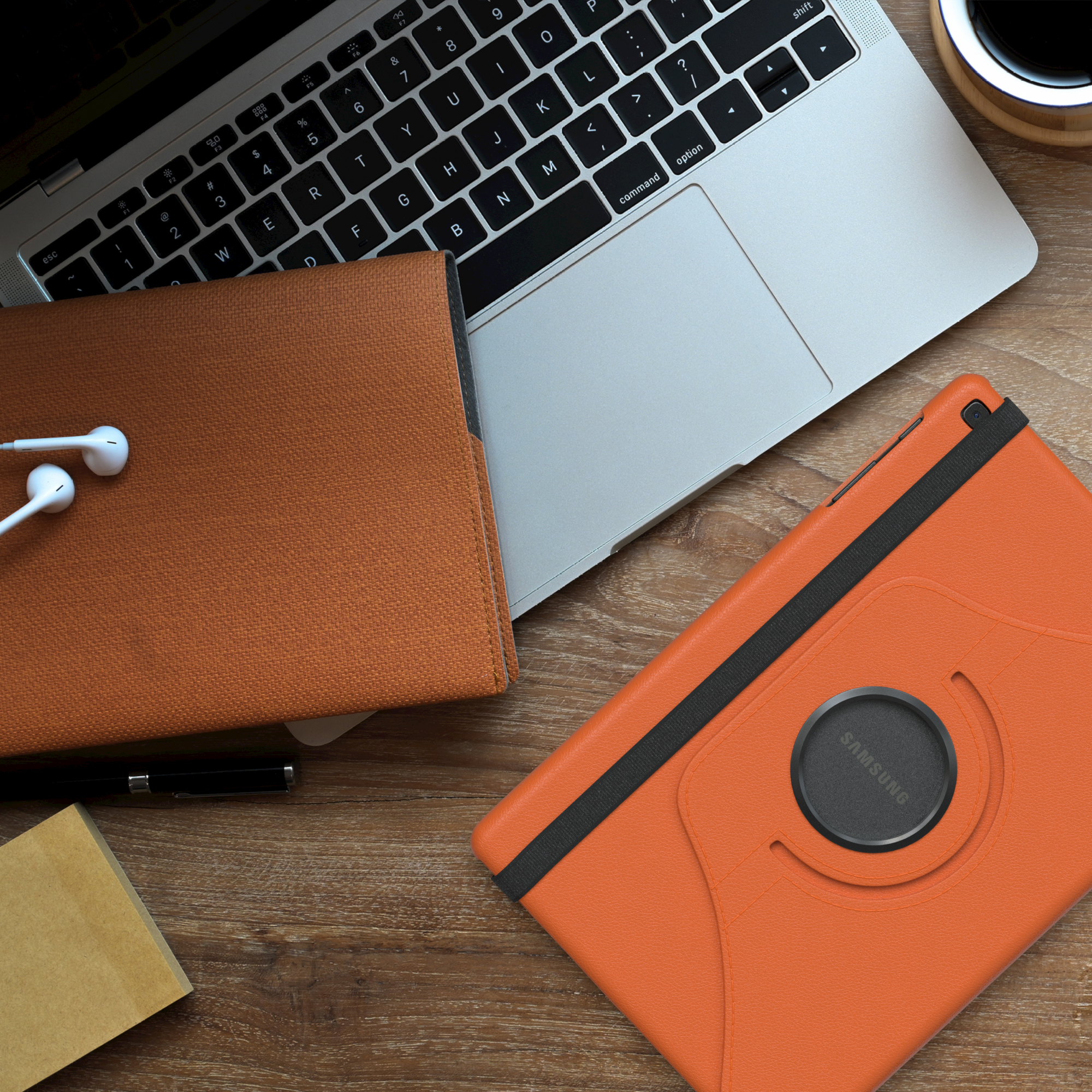Tablet und Hülle auf einem Holzschreibtisch, neben Laptop, Kopfhörern und Kaffeetasse.