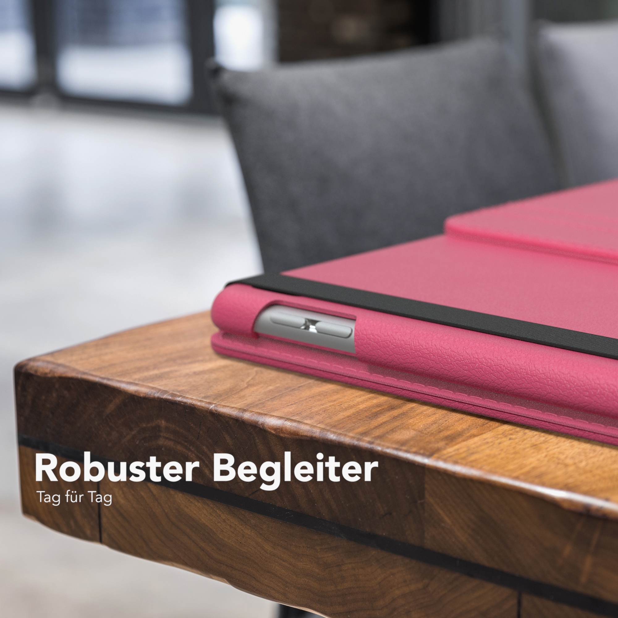 Rosa Tablet-Hülle auf einem Holztisch. Im Hintergrund ist ein grauer Stuhl zu sehen.