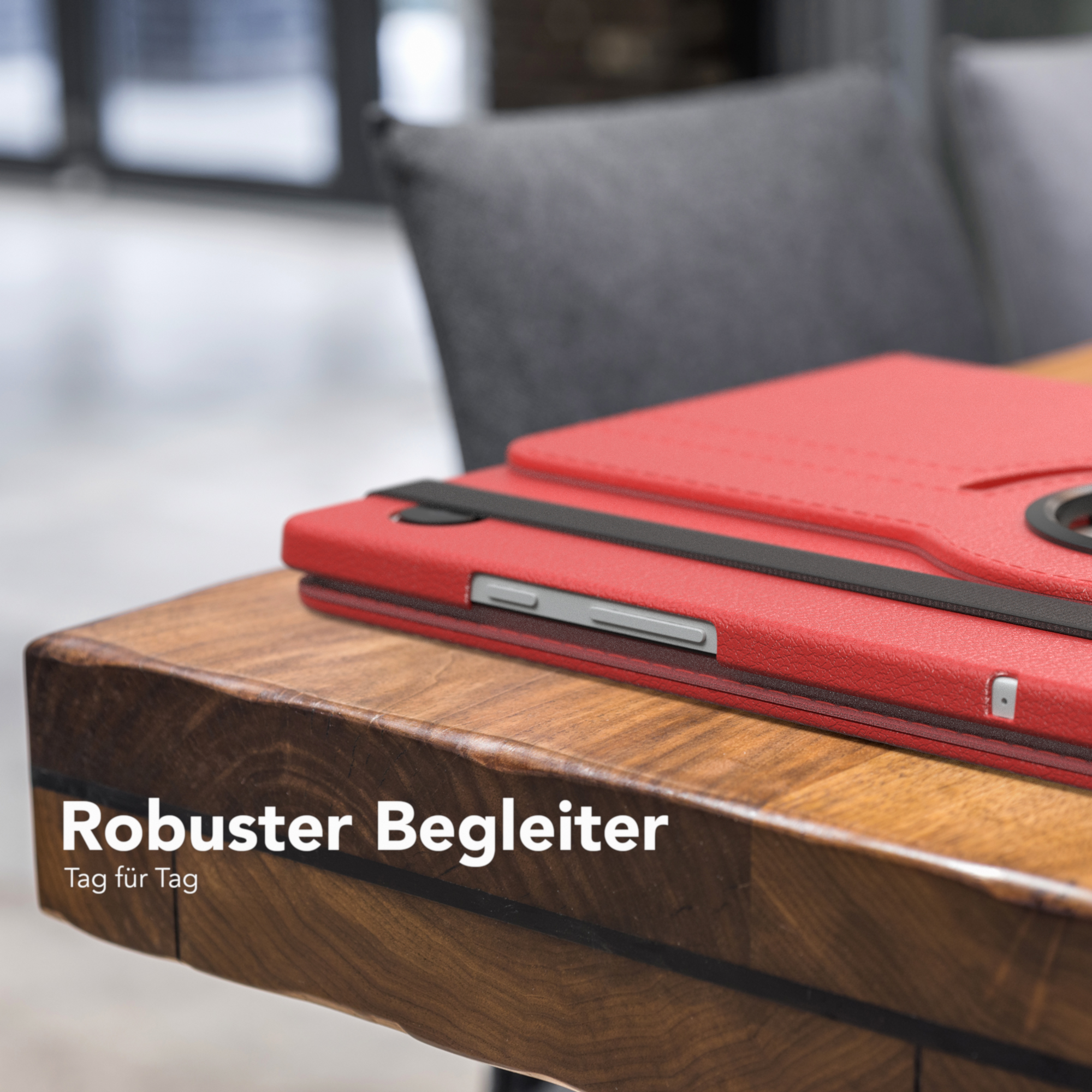 Eine rote Tablethülle auf einem Holztisch, mit einem teilweise sichtbaren Tablet.