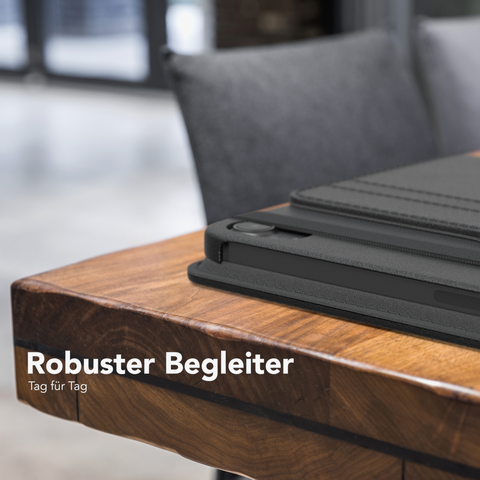 Tablet auf einem Holztisch. Schwarze Hülle, der Text Robust Begleiter und Tag für Tag sind sichtbar.