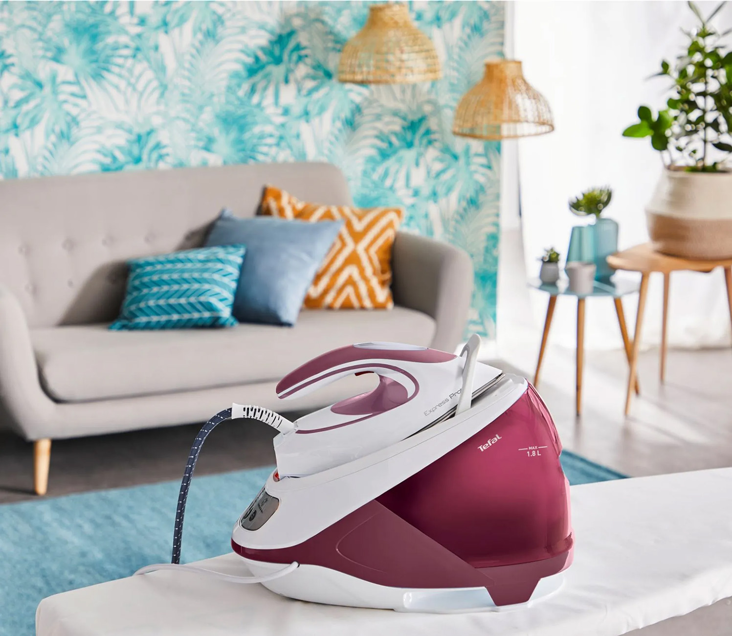 Białe i bordowe żelazko na desce do prasowania. Przytulny salon z sofą i roślinami.