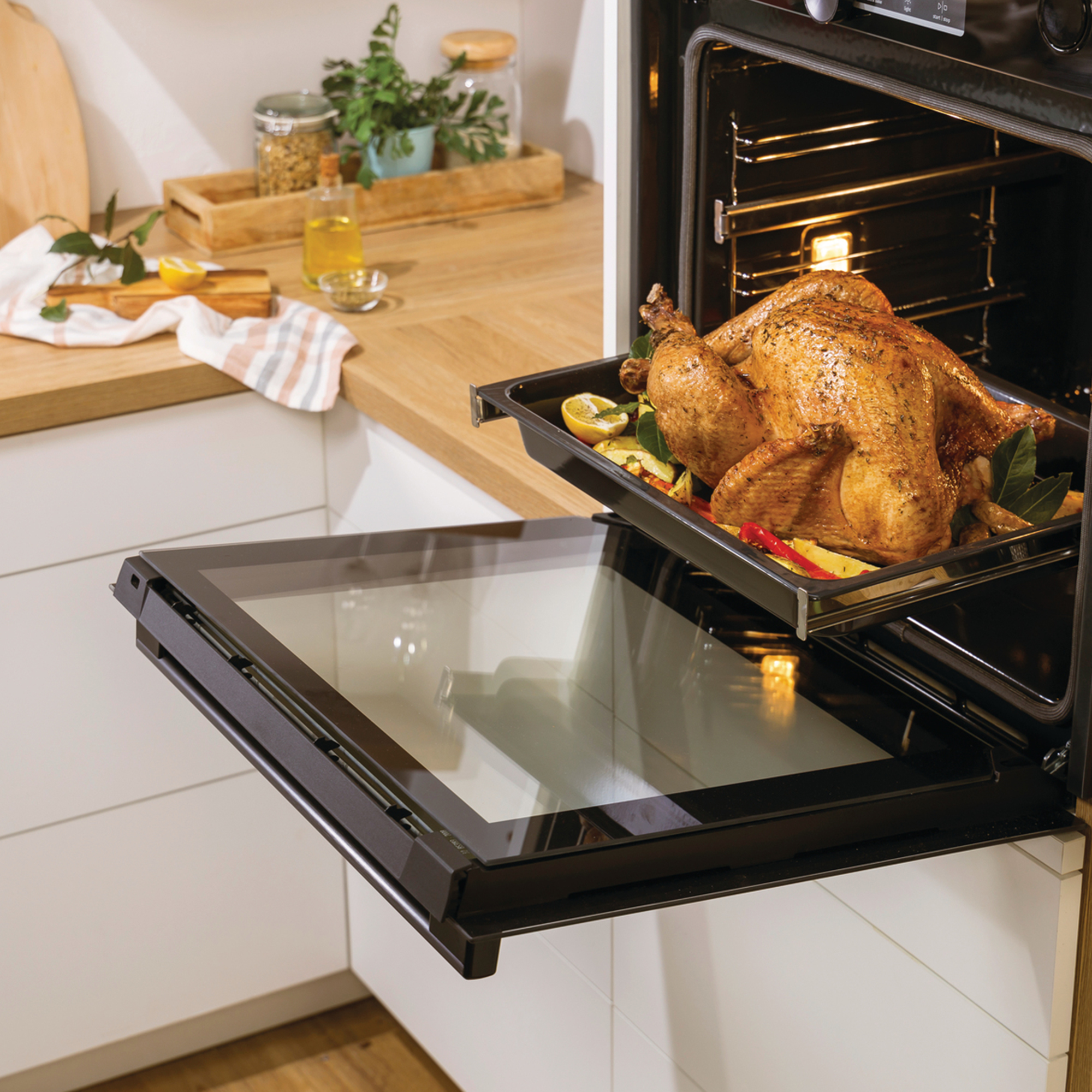 Piekarnik z otwartymi drzwiami, pokazujący pieczonego indyka na tacy z warzywami.