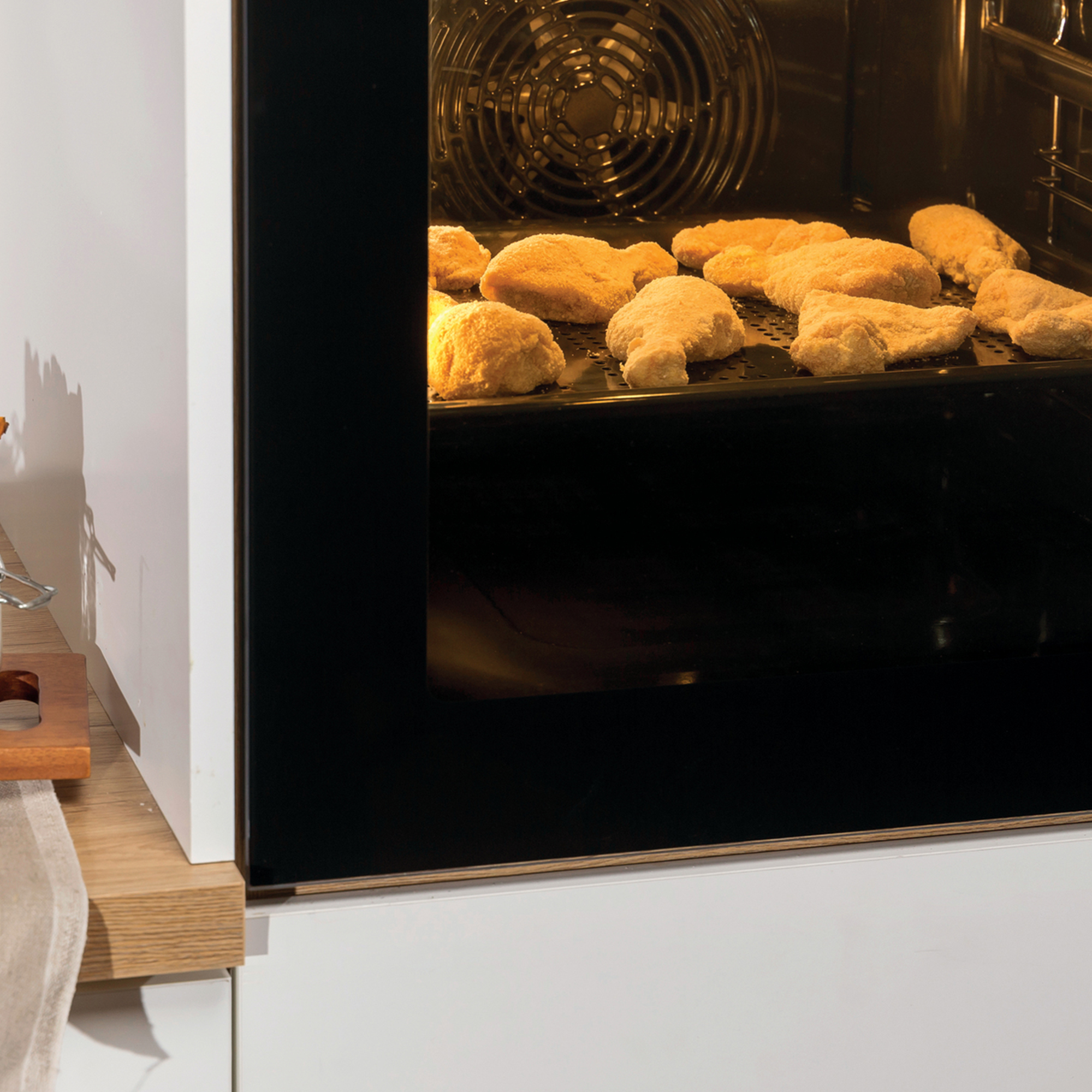 Piekarnik z zamrożonymi kawałkami kurczaka na tacy.