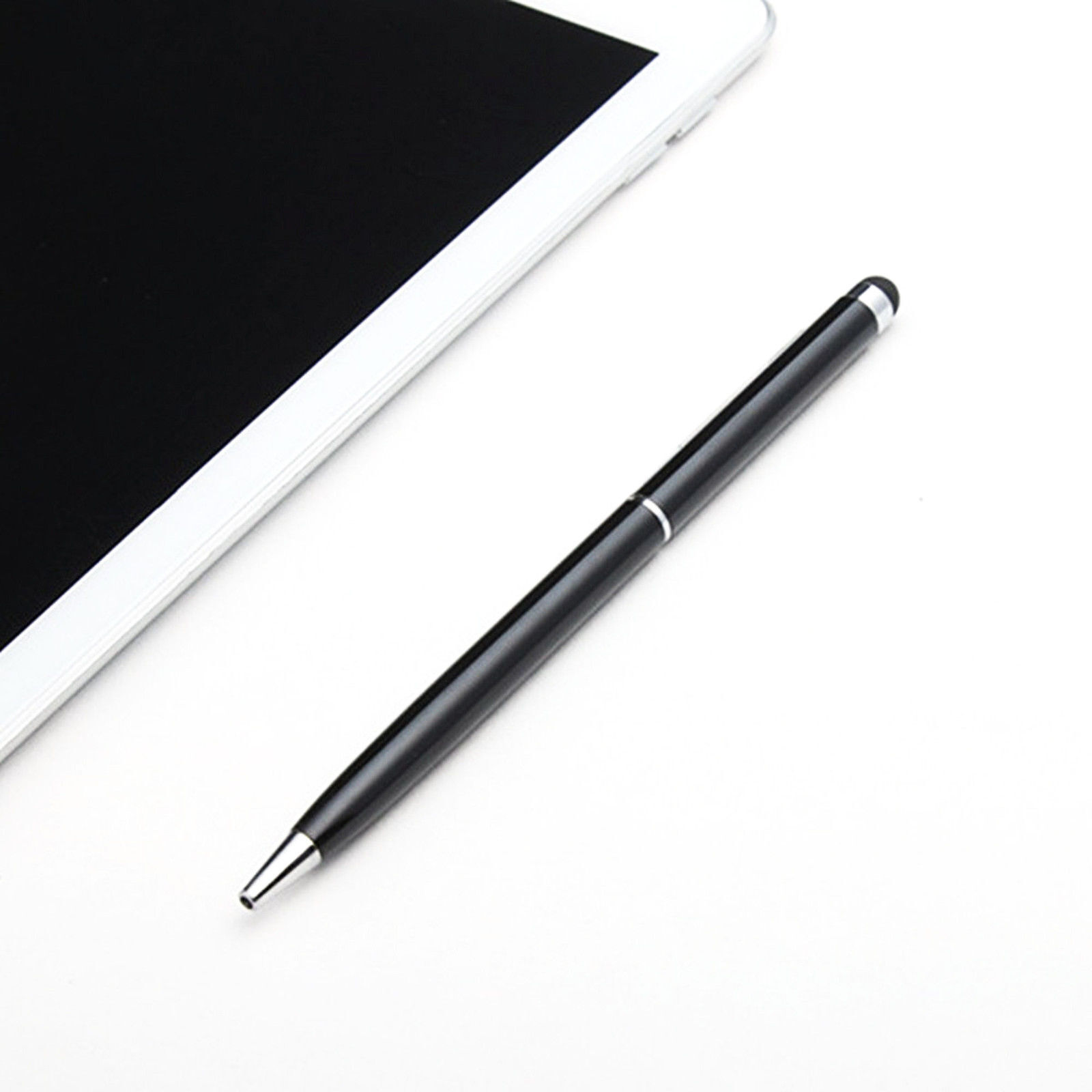 Schwarzer Stift neben einem Tablet auf weißer Oberfläche.