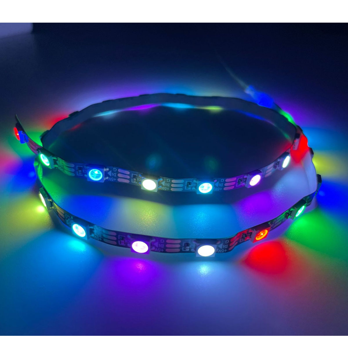 Ein flexibles LED-Band, das mit mehreren Farben beleuchtet wird, wird auf einer dunkelblauen Oberfläche gezeigt.