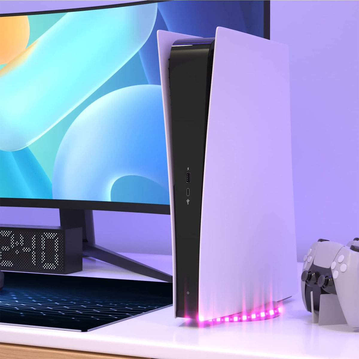 Eine weiße und schwarze Spielekonsole steht auf einem Schreibtisch mit Monitor und Controller.