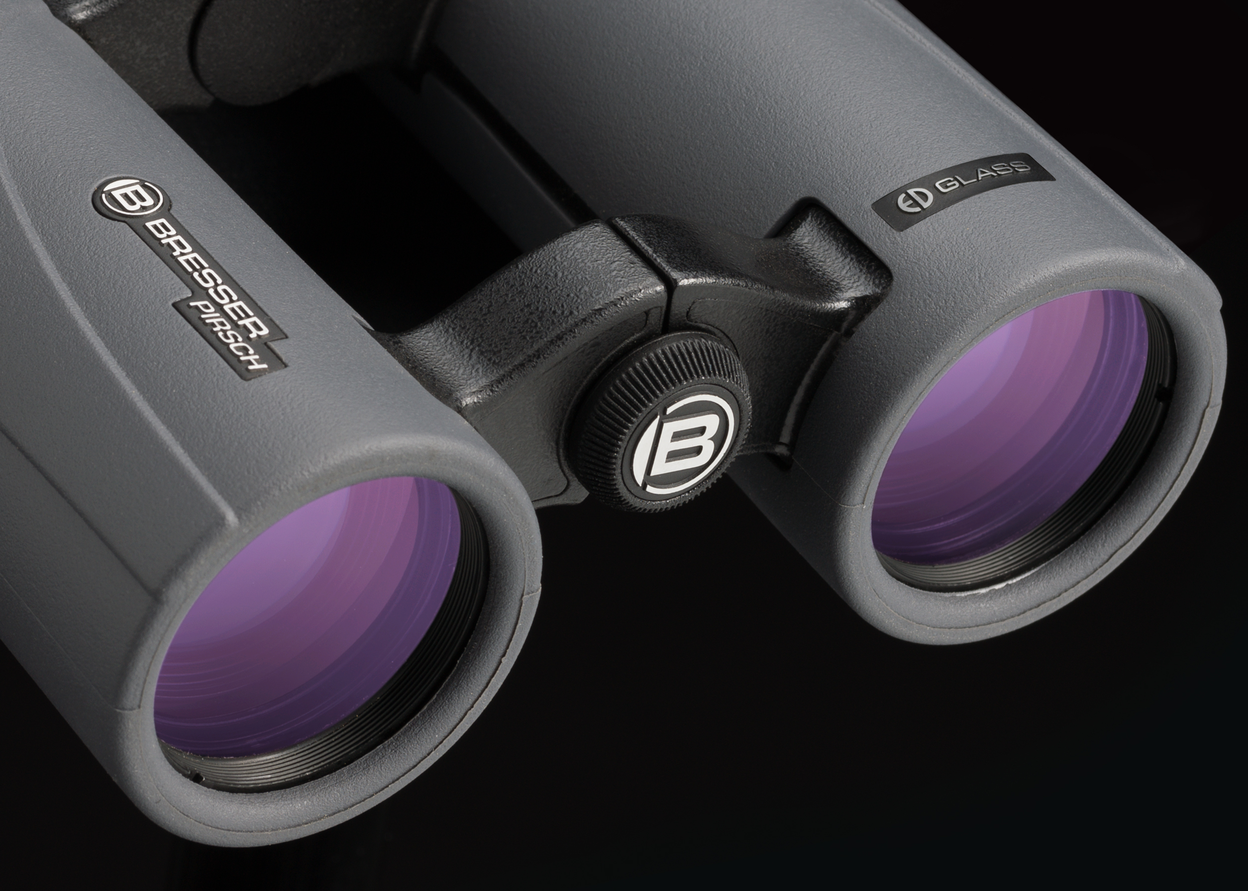 Graues Fernglas mit violetten Linsen auf schwarzem Hintergrund. Marke Bresser Pirsch.