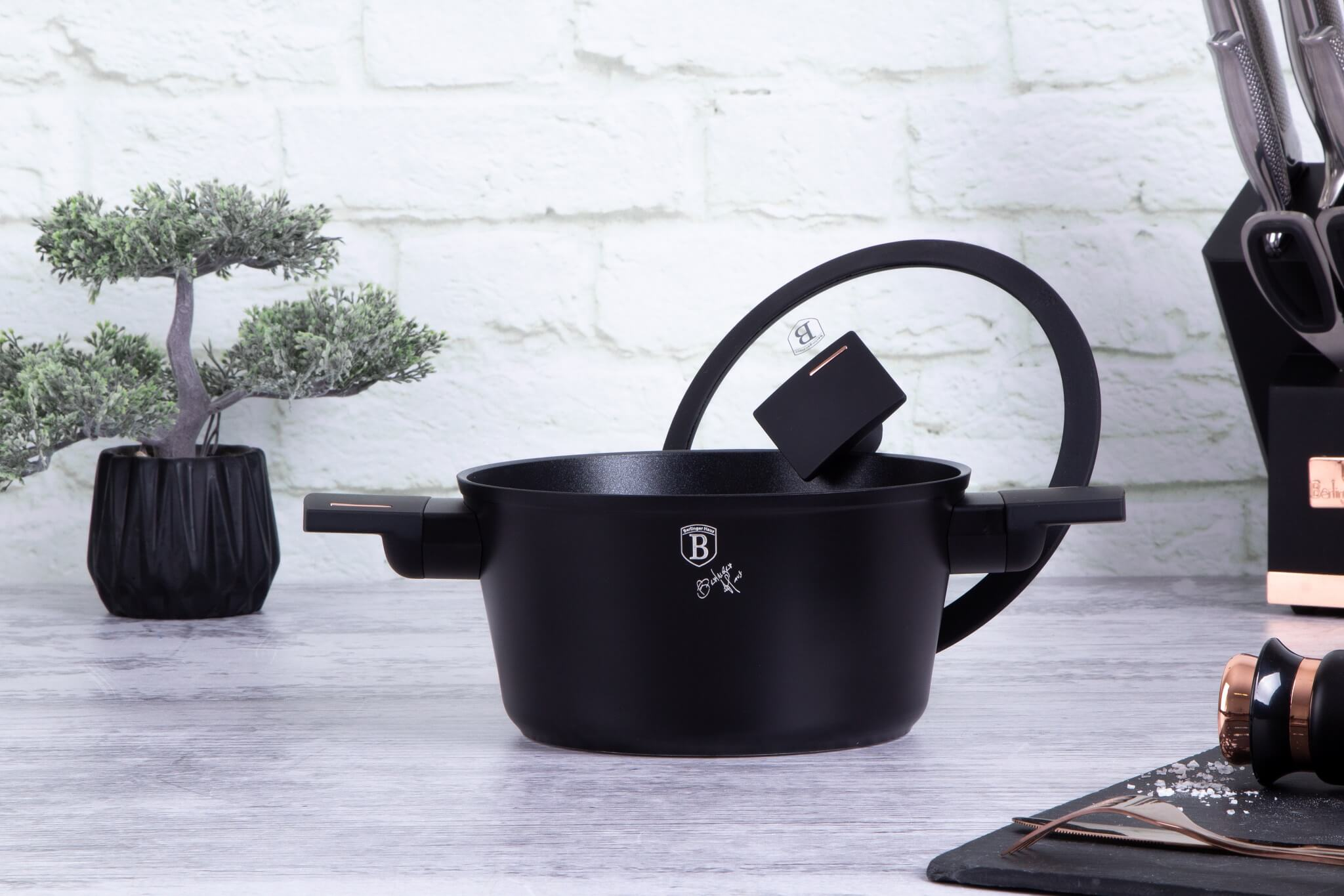 Schwarzer Topf mit Glasdeckel auf Tisch. Kleiner Bonsai und Messer im Hintergrund.