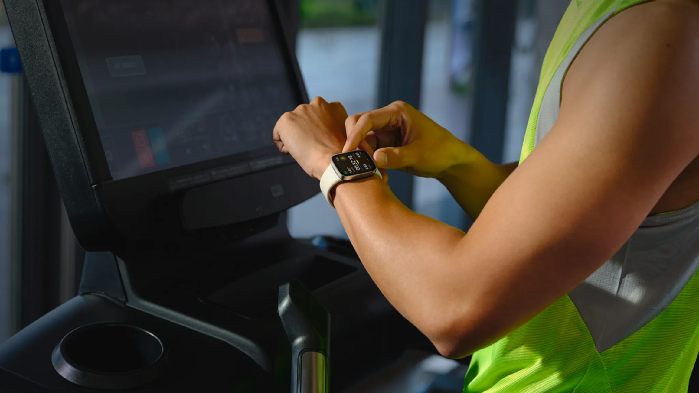 Persona sul tapis roulant. Stanno guardando uno smartwatch al polso.