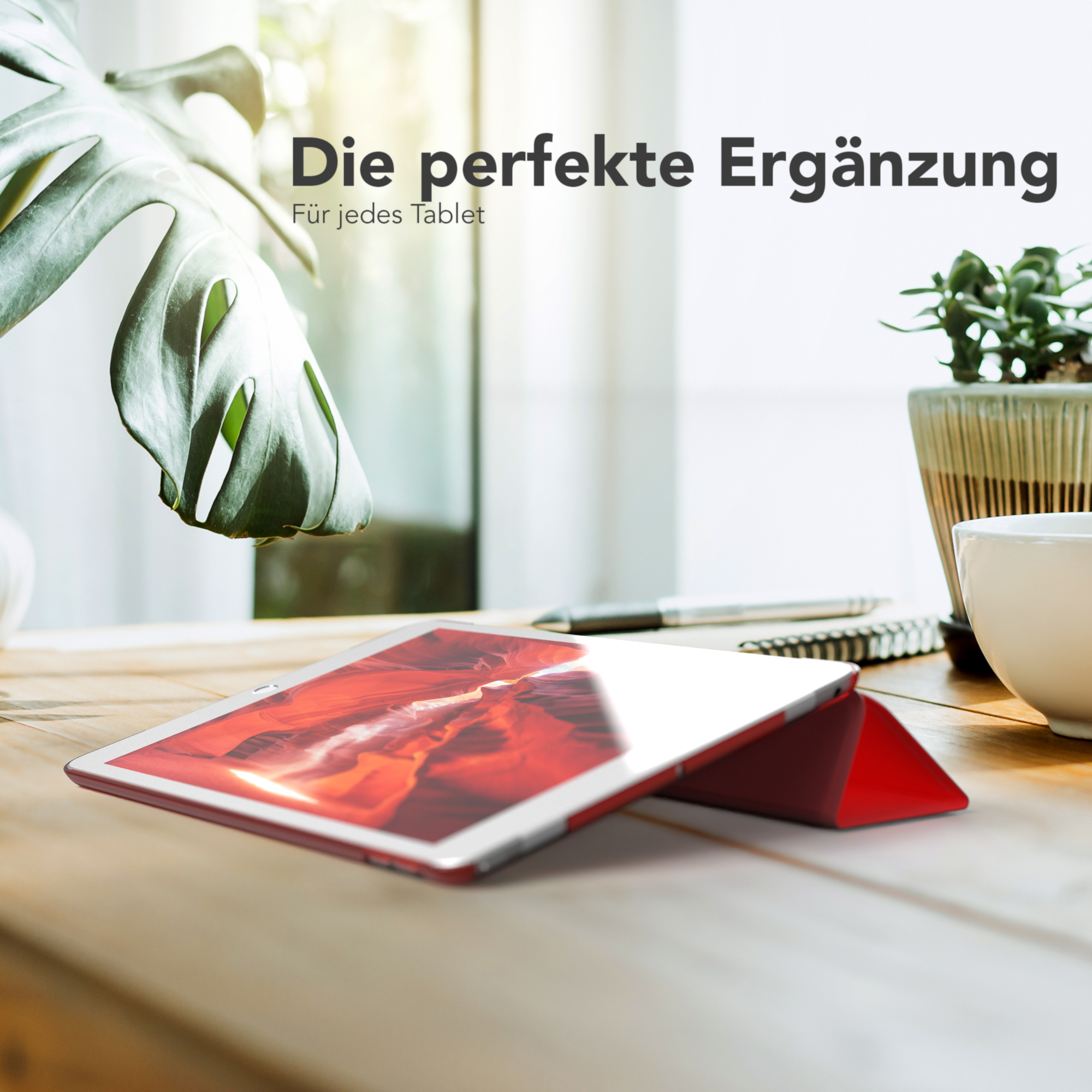 Tablet in roter Hülle auf Holztisch mit Pflanze und Tasse.