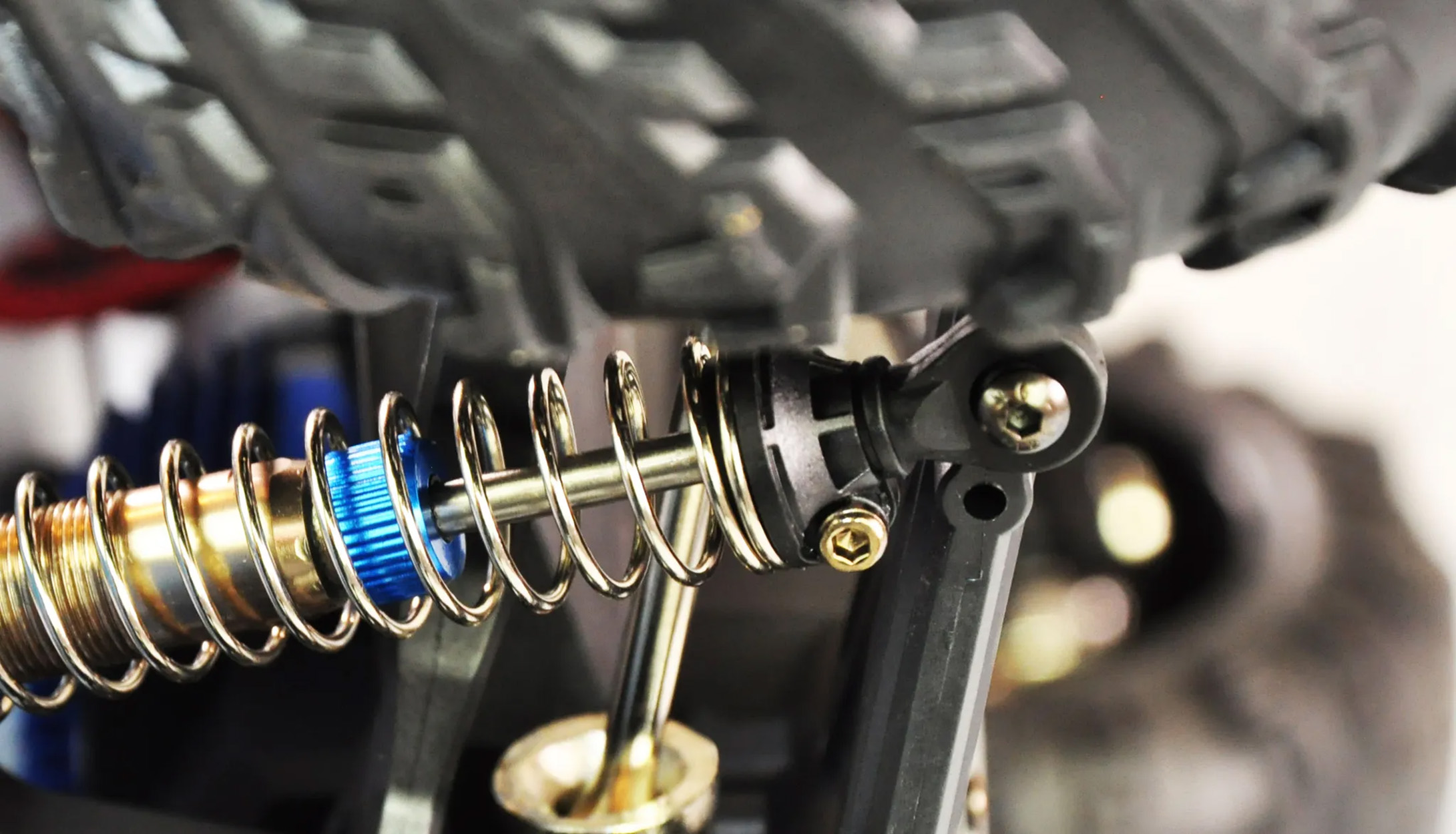 Nahaufnahme einer Autosuspension. Eine blaue Feder ist um einen goldfarbenen Stoßdämpfer gewickelt.