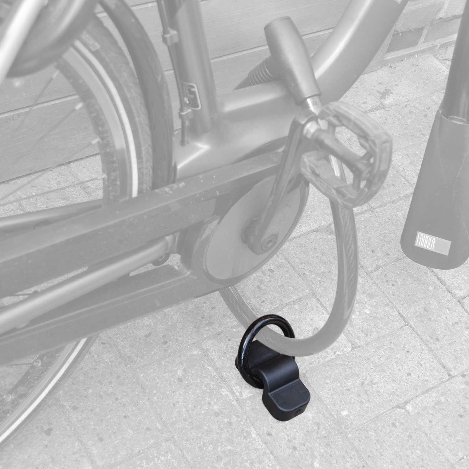 Ein schwarzes Fahrradschloss, das ein Fahrradrad am Rahmen auf einer Ziegeloberfläche sichert.