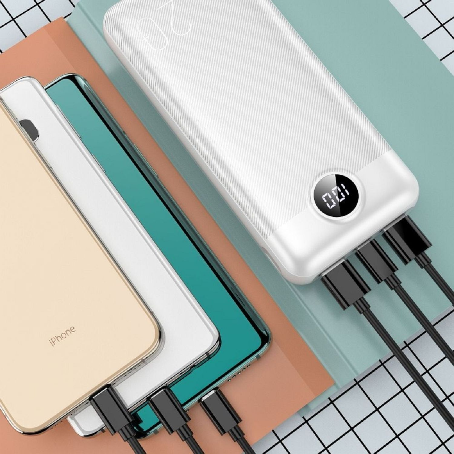 Weiße Powerbank mit vier schwarzen Ladekabeln. Drei Telefone befinden sich in der Nähe der Powerbank. Bunter Hintergrund.