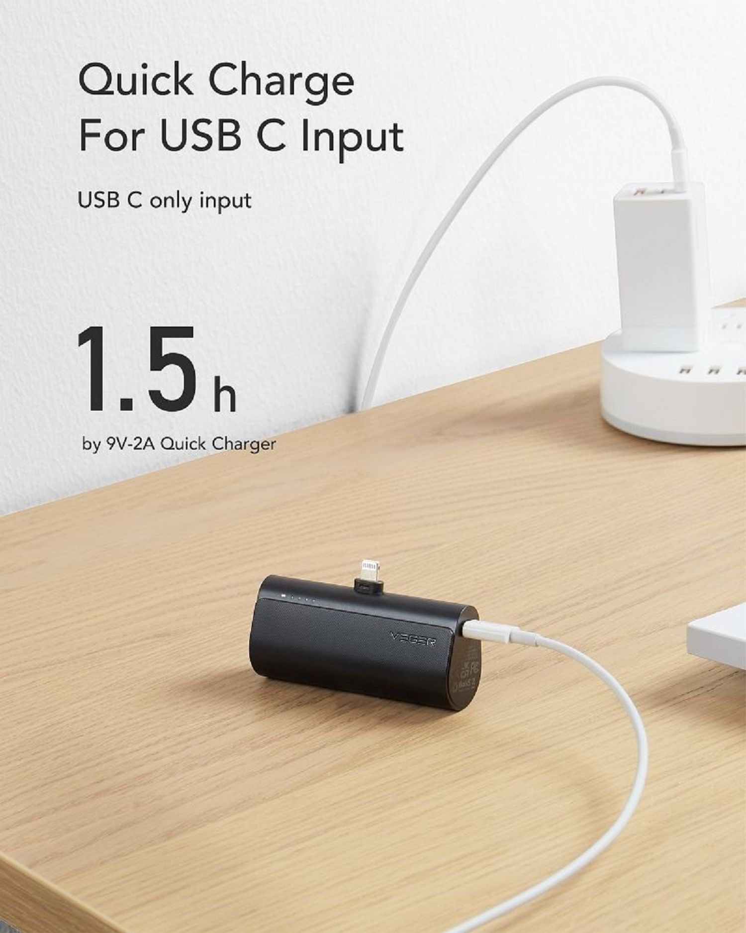 Schwarzes Ladegerät mit angeschlossenem USB-C-Kabel auf Holzoberfläche.