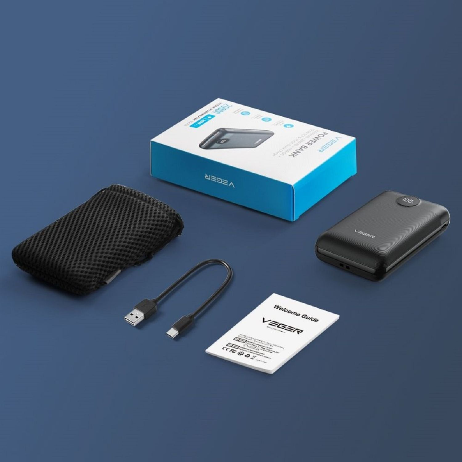 Powerbank und Zubehör. Schwarze Powerbank, Ladekabel und Bedienungsanleitung auf blauer Oberfläche.