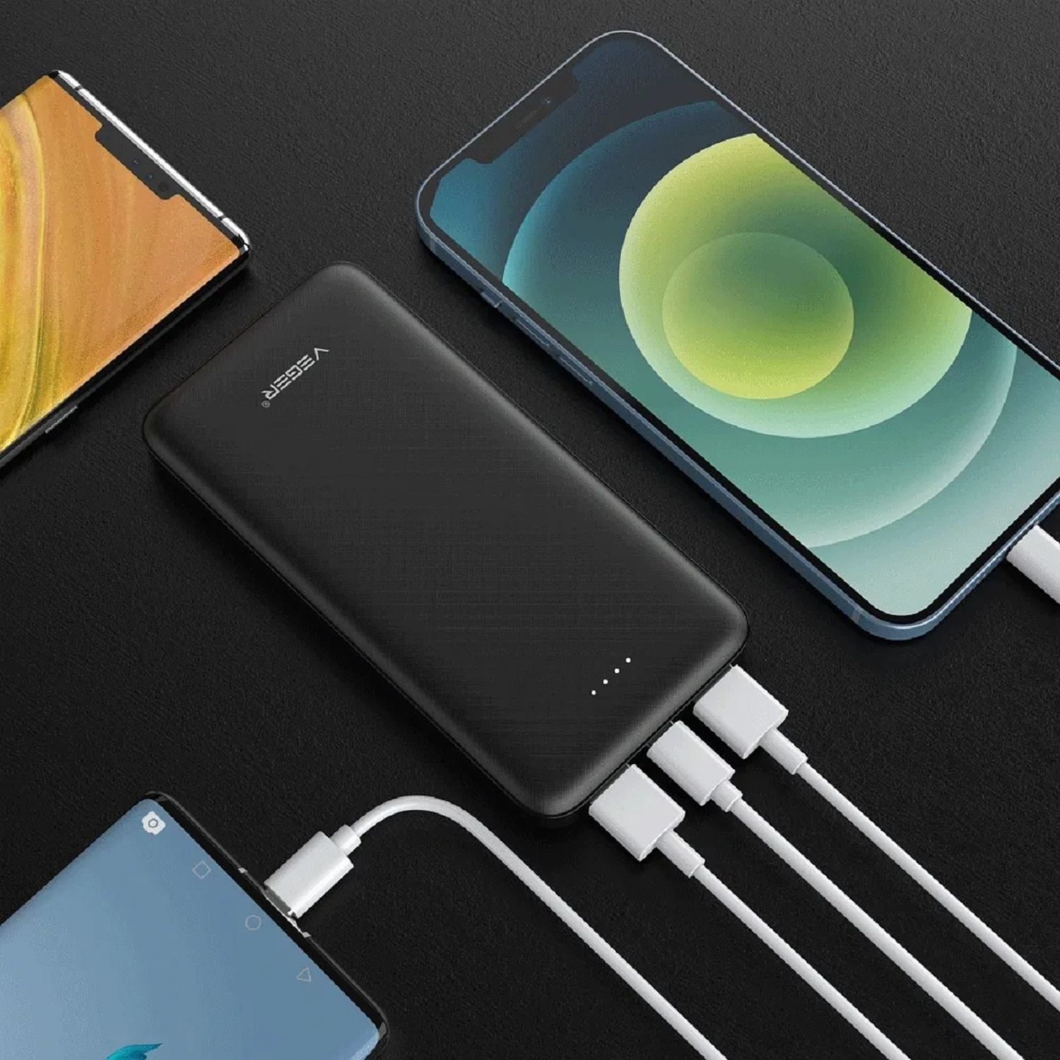 Schwarze Powerbank, verbunden mit drei Handys über weiße Ladekabel auf schwarzem Untergrund.