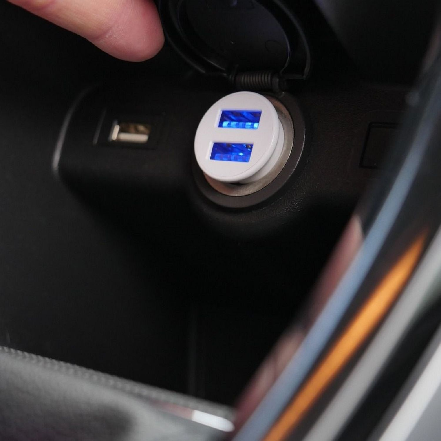 Der USB-Ladeanschluss eines Autos mit blau beleuchtetem Ladegerät ist in einem dunklen Innenraum geöffnet.